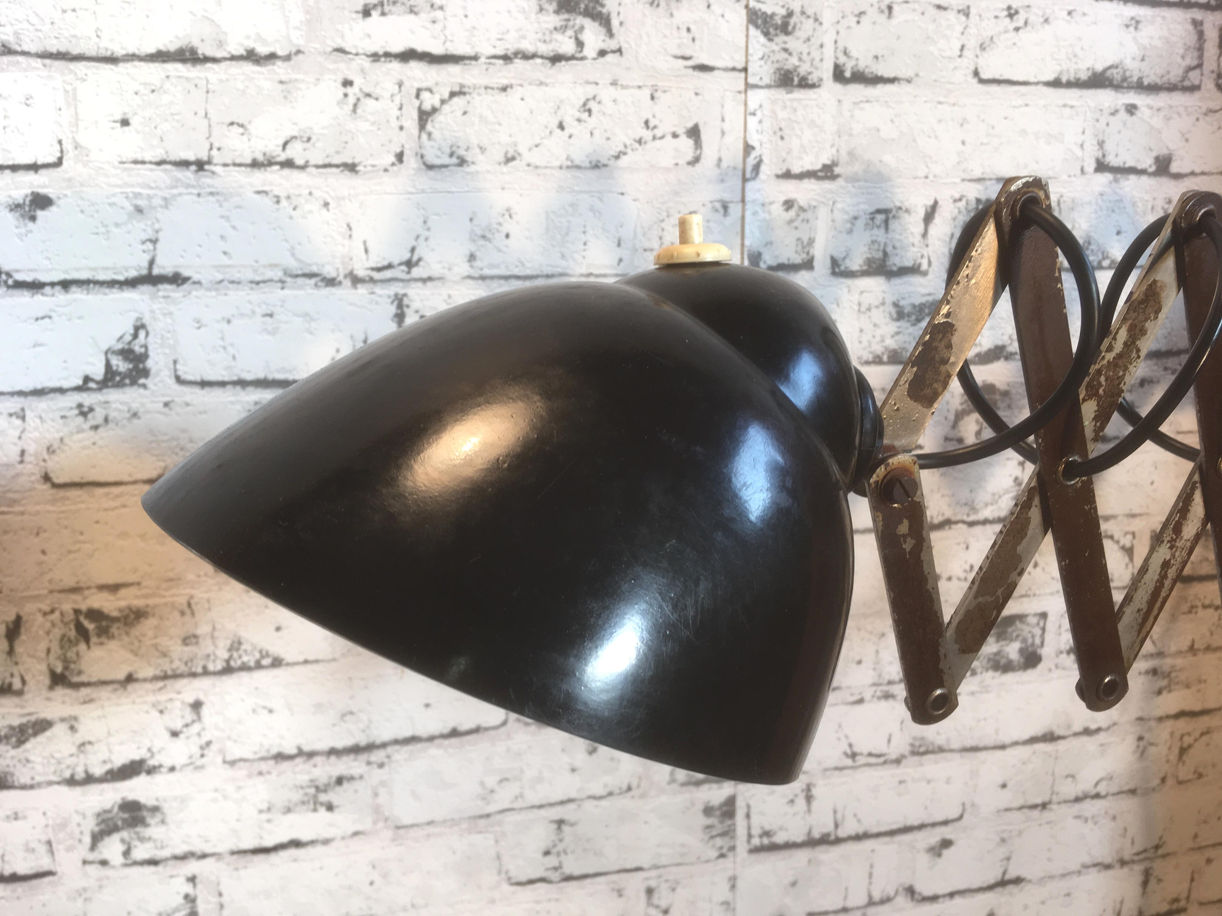 This vintage industrial scissor lamp was produced during the 1950s. Lamp has brown Bakelite shade. Iron scissor arm is extendable and can be turned sideways. The switch is located directly on the shade. Original socket for E 27 bulbs. Fully