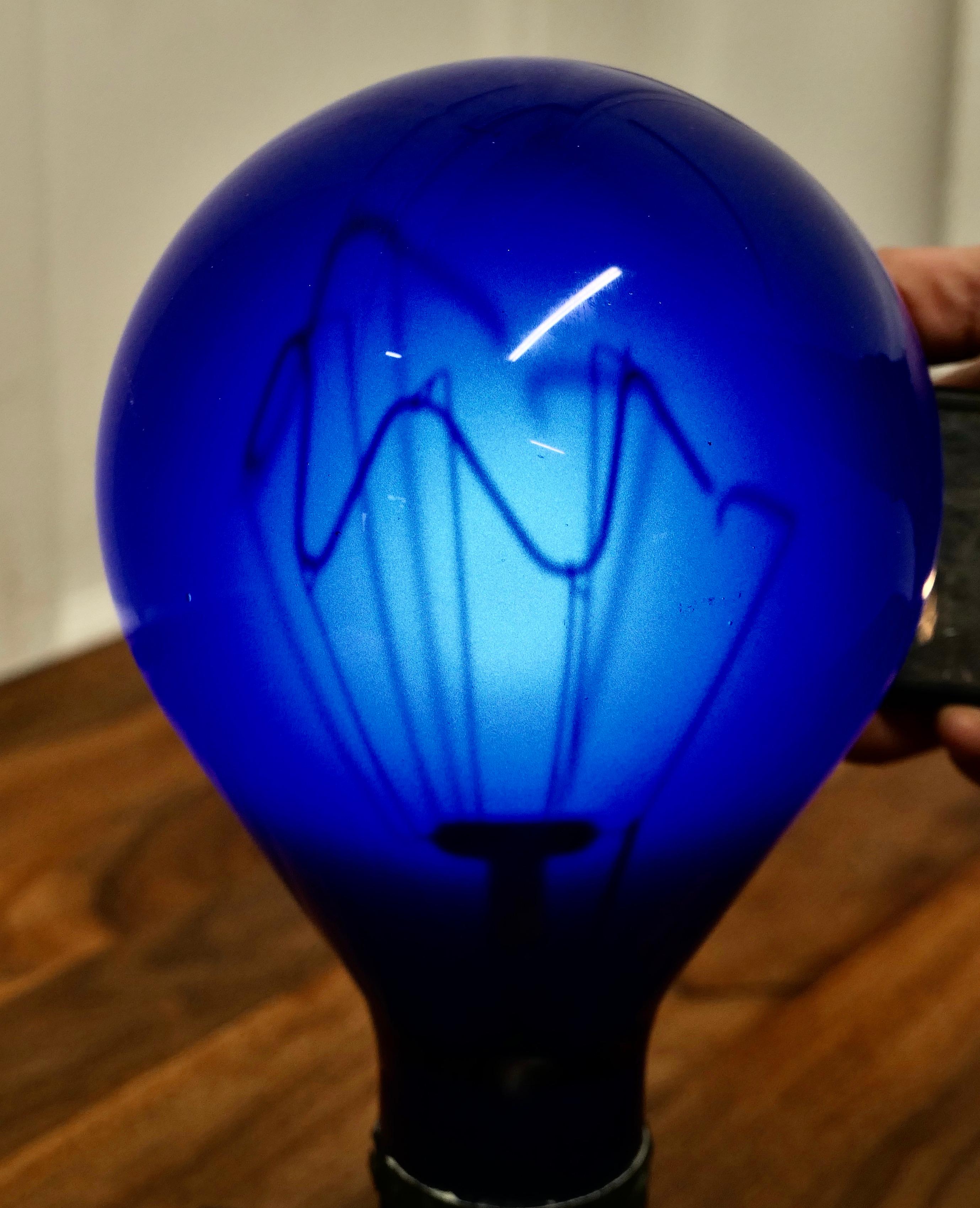 Industrial Sculpture Made From an Early American Light Bulb

This is not a working Light Bulb, it is in Blue glass and has been set on a rectangular plinth and when lit from behind you can see the internal element
The Bulb comes from the USA and is
