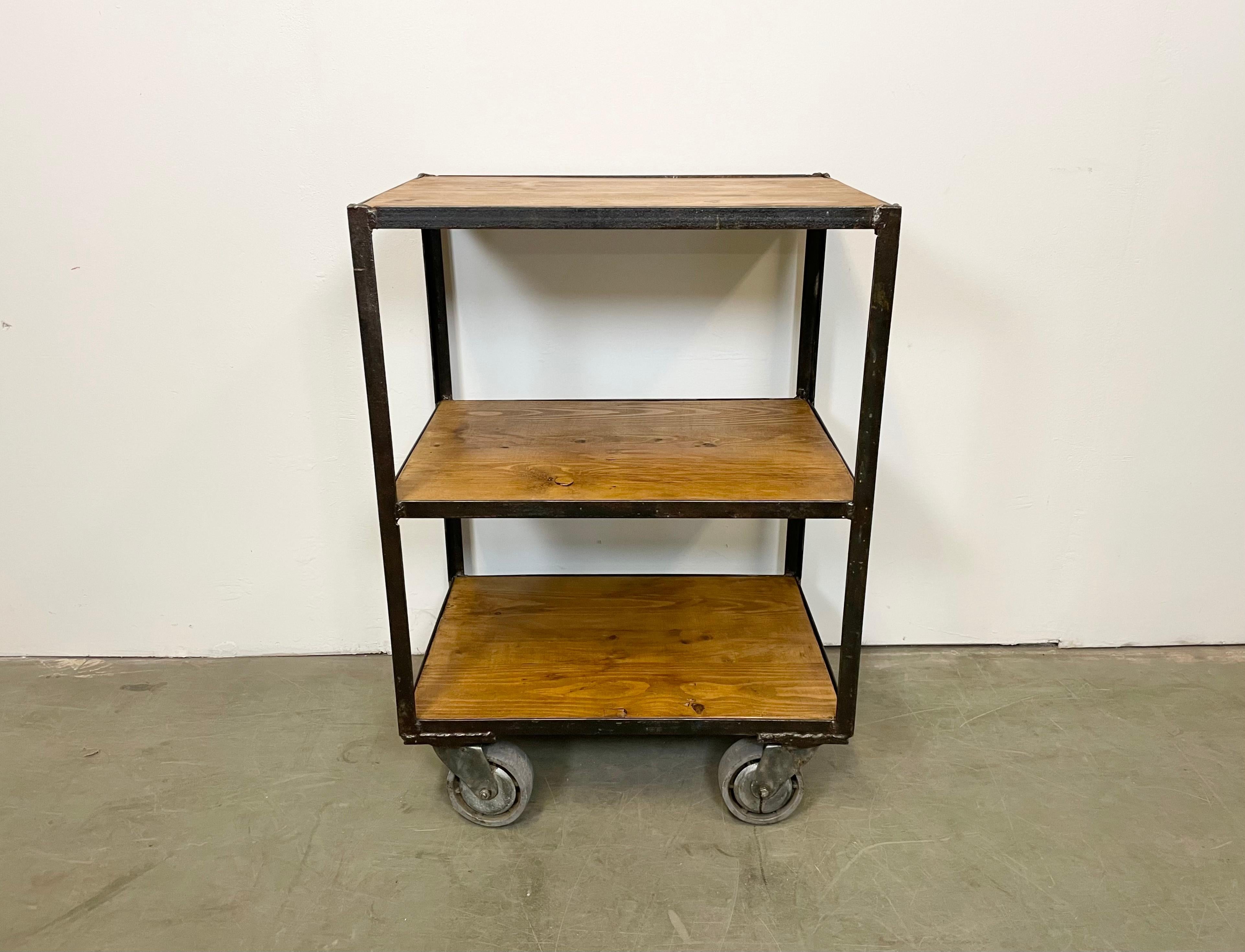 Industrial shelf from the 1960s. It features an iron construction, a three wooden shelves and a four original wheels. The weight of the shelf is 23 kg.