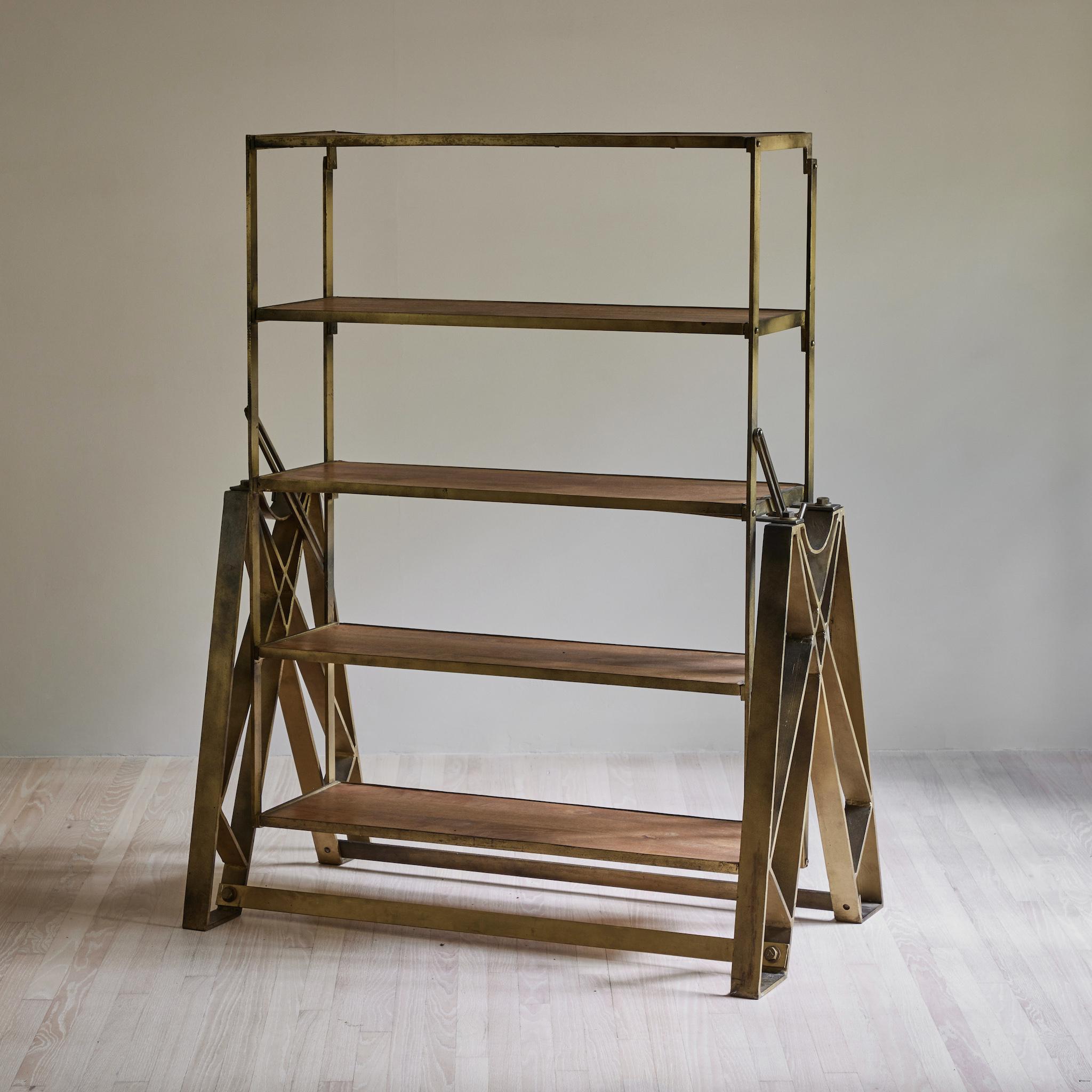 Turn-of-the-century English industrial shelves. A masterpiece of engineering, these stylish shelves can be adjusted to extend into a table. The sturdy metal framework supports five wood inserted shelves, which lie flush when extended as a tabletop.