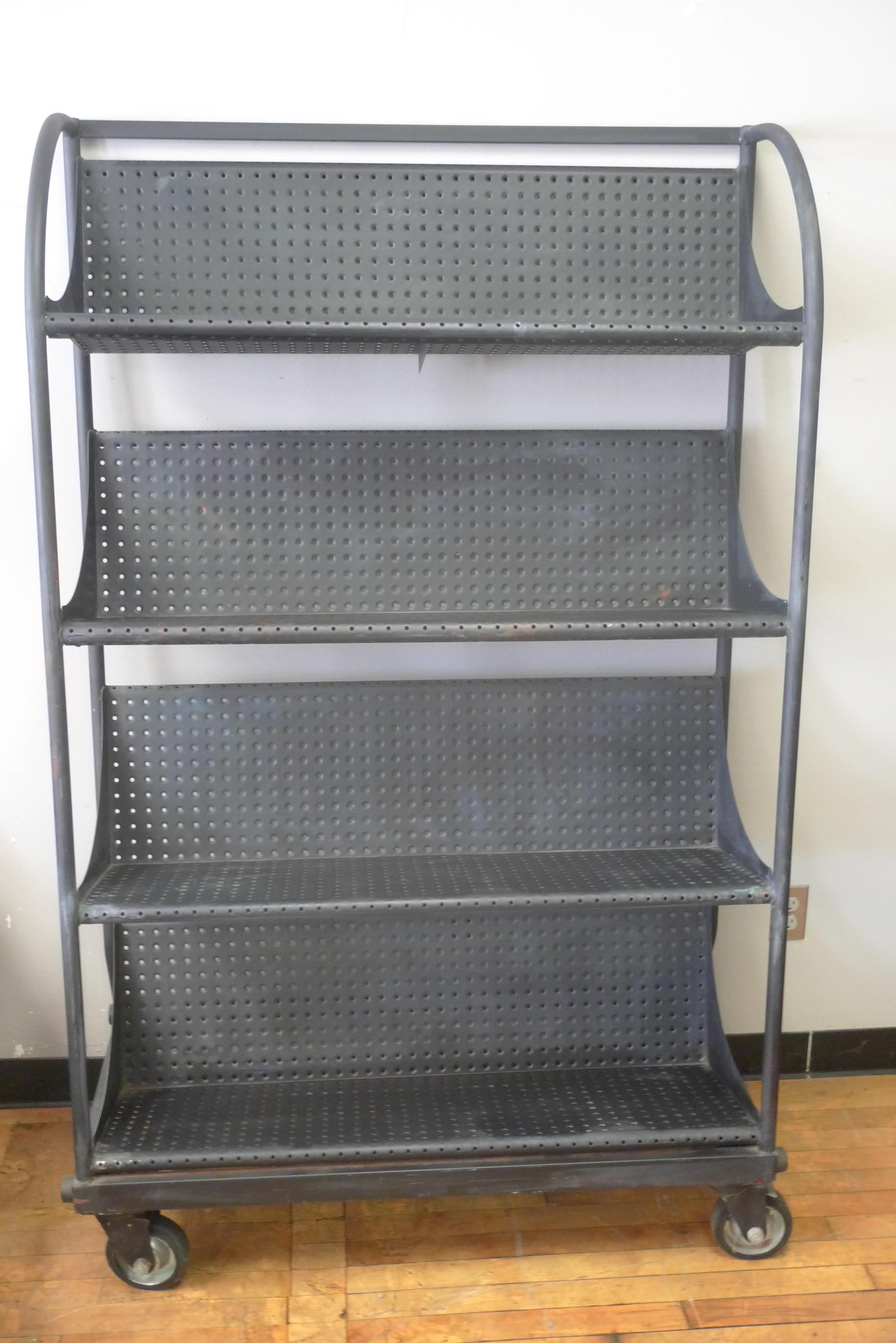 Industrial shelving unit on wheels with perforated steel shelves. Painted an as-found matte black, this unit scoots around nicely on pivoting rubber wheels but but also stands in place securely when wheels are locked. Even has rubber bumper pads to