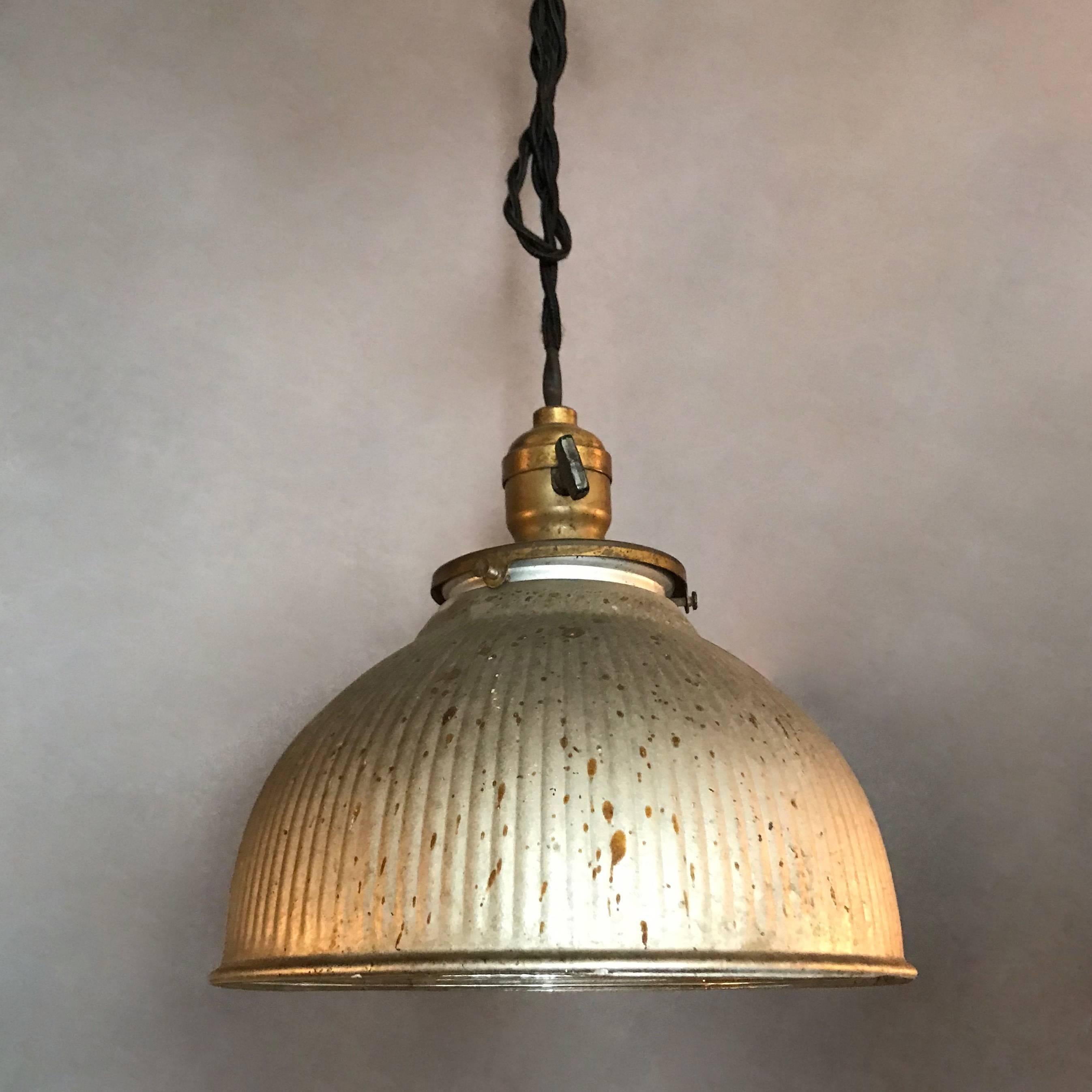 Industrial pendant light features a X-Ray mercury glass, dome shade painted silver on it's exterior with brass switch fitter that is newly wired with 36 inches of black braided cloth cord to accept up to a 200 watt bulb.