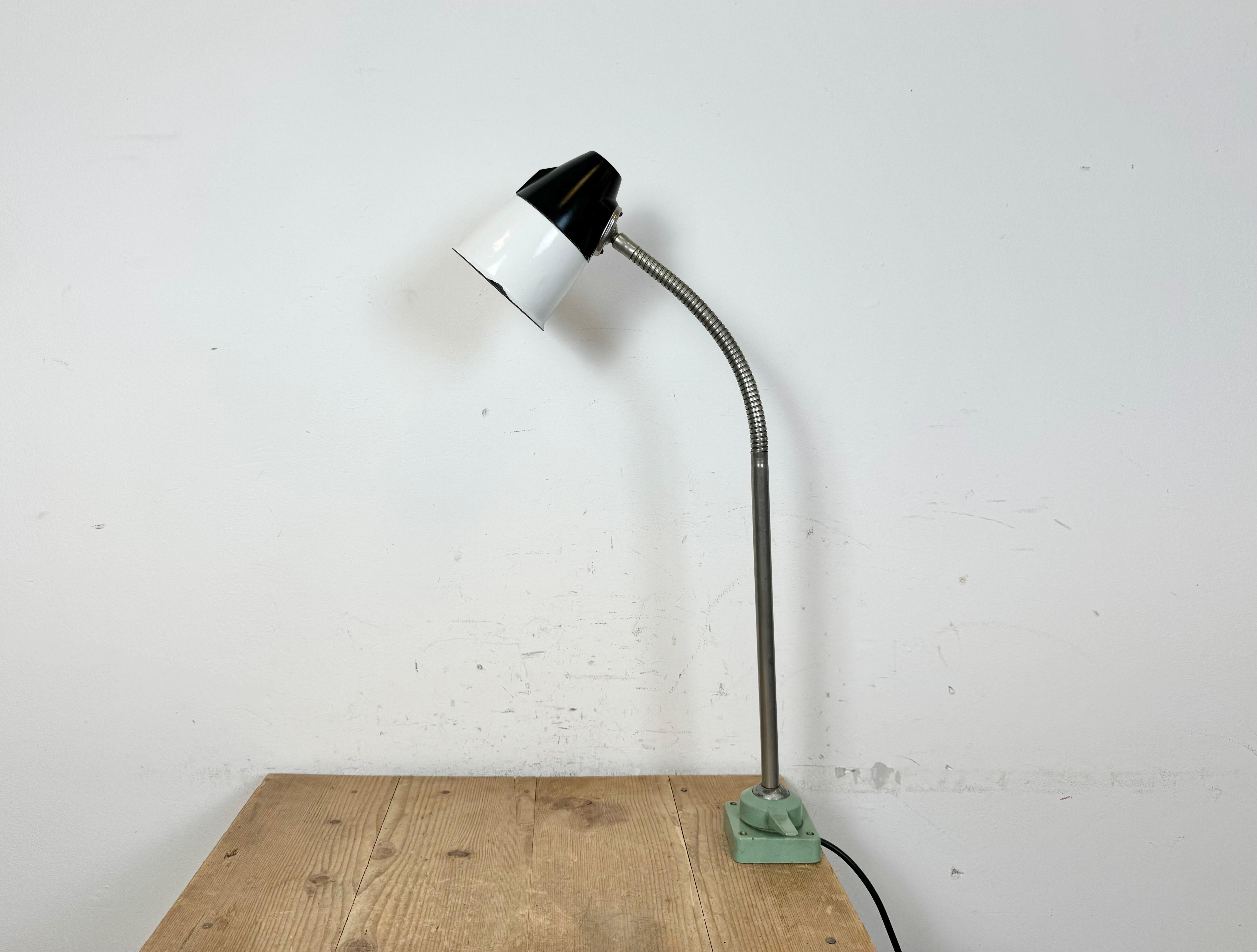 This industrial adjustable gooseneck work table lamp was made in former Soviet Union during the 1960s. The lamp has a white enamel iron shade, a bakelite top, a chrome plated gooseneck and iron base. The porcelain socket requires standard E27/ E27