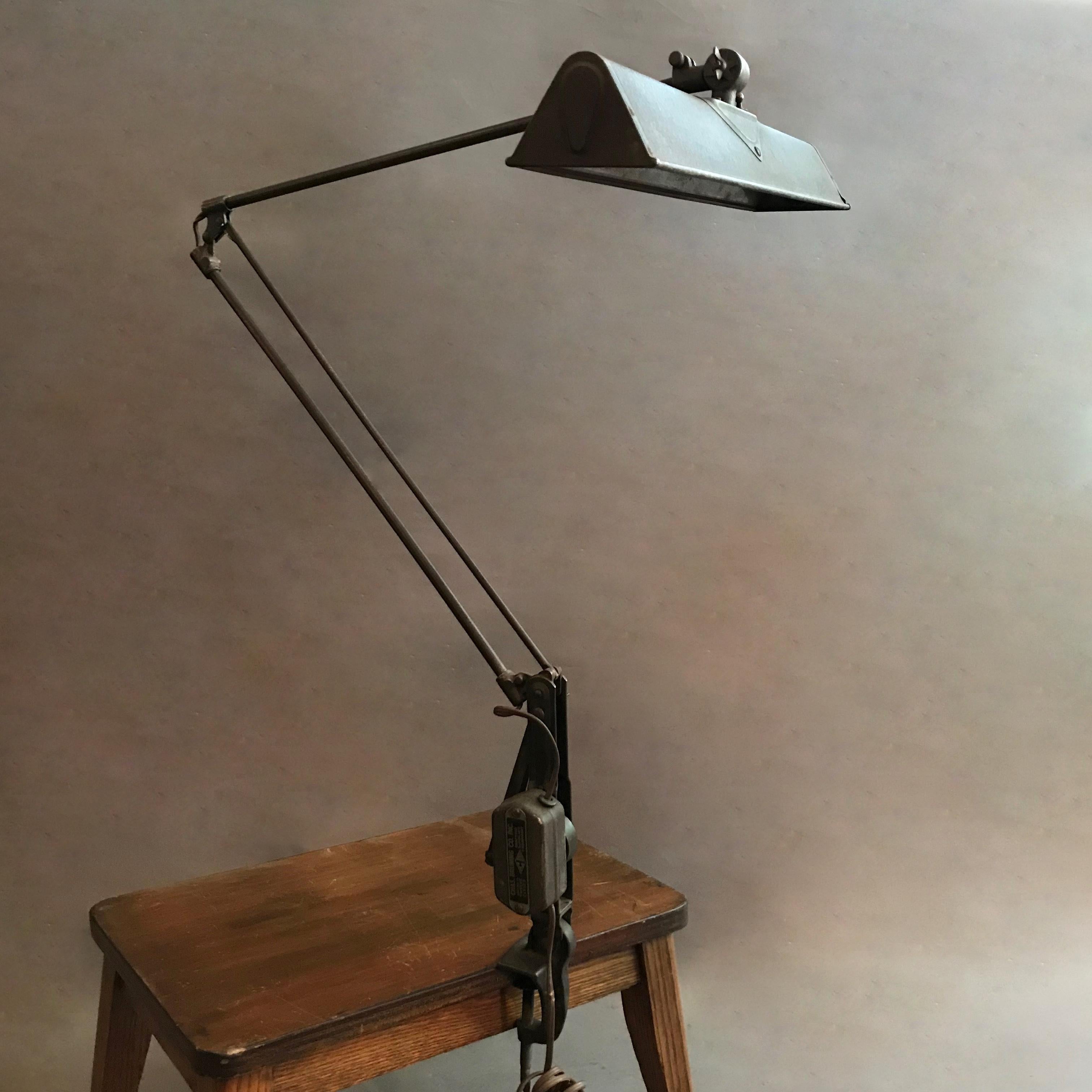Industrial, architect's, drafting work lamp is painted steel with reflective shade interior features adjustable spring-arm movement and surface clamp. The lamp accepts two medium socket bulbs up to 75 watts each.