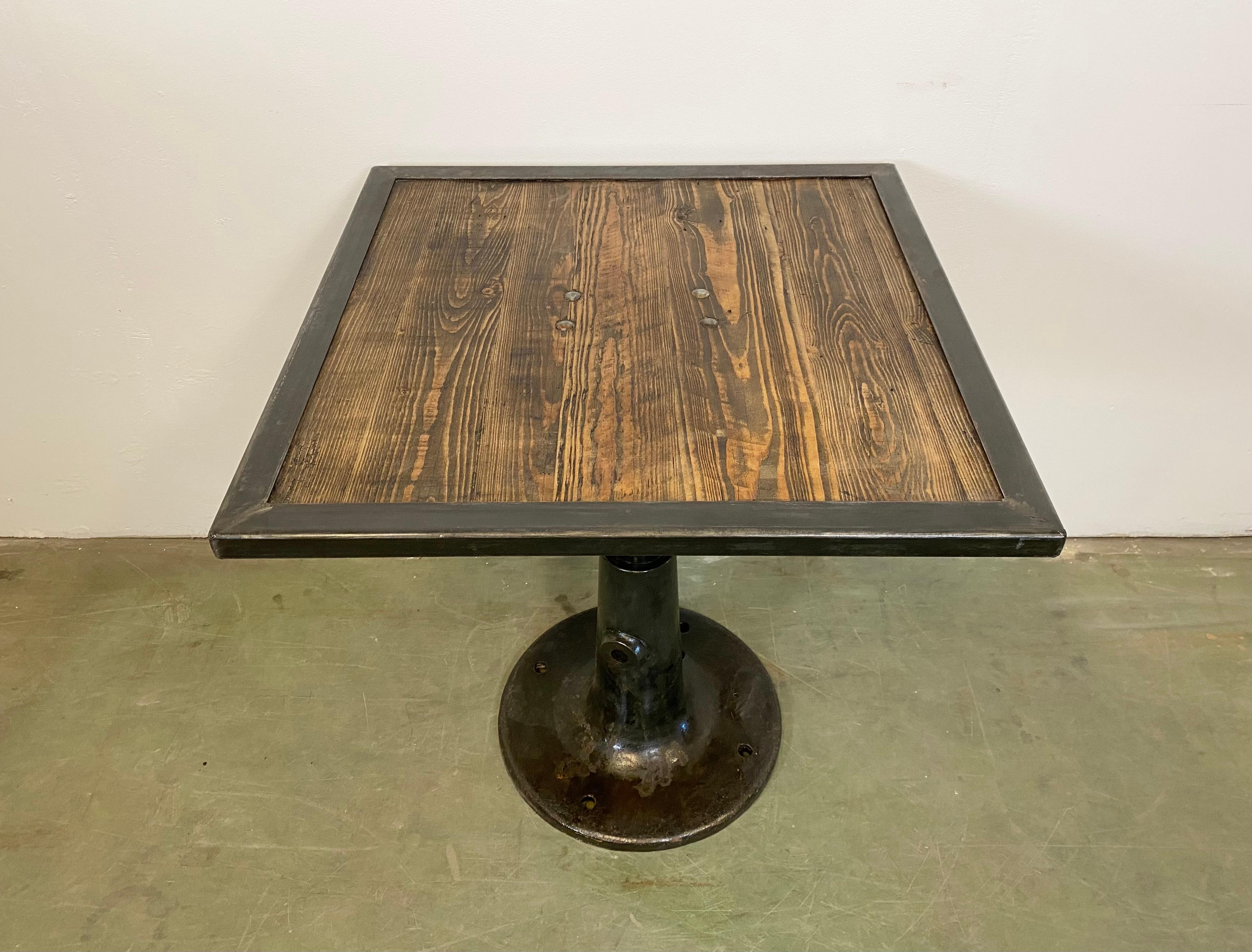 Vintage Industrial square coffee table from the 1960s. It features a black cast iron leg and a solid wooden plate with a black iron frame. The weight of the table is 50 kg.