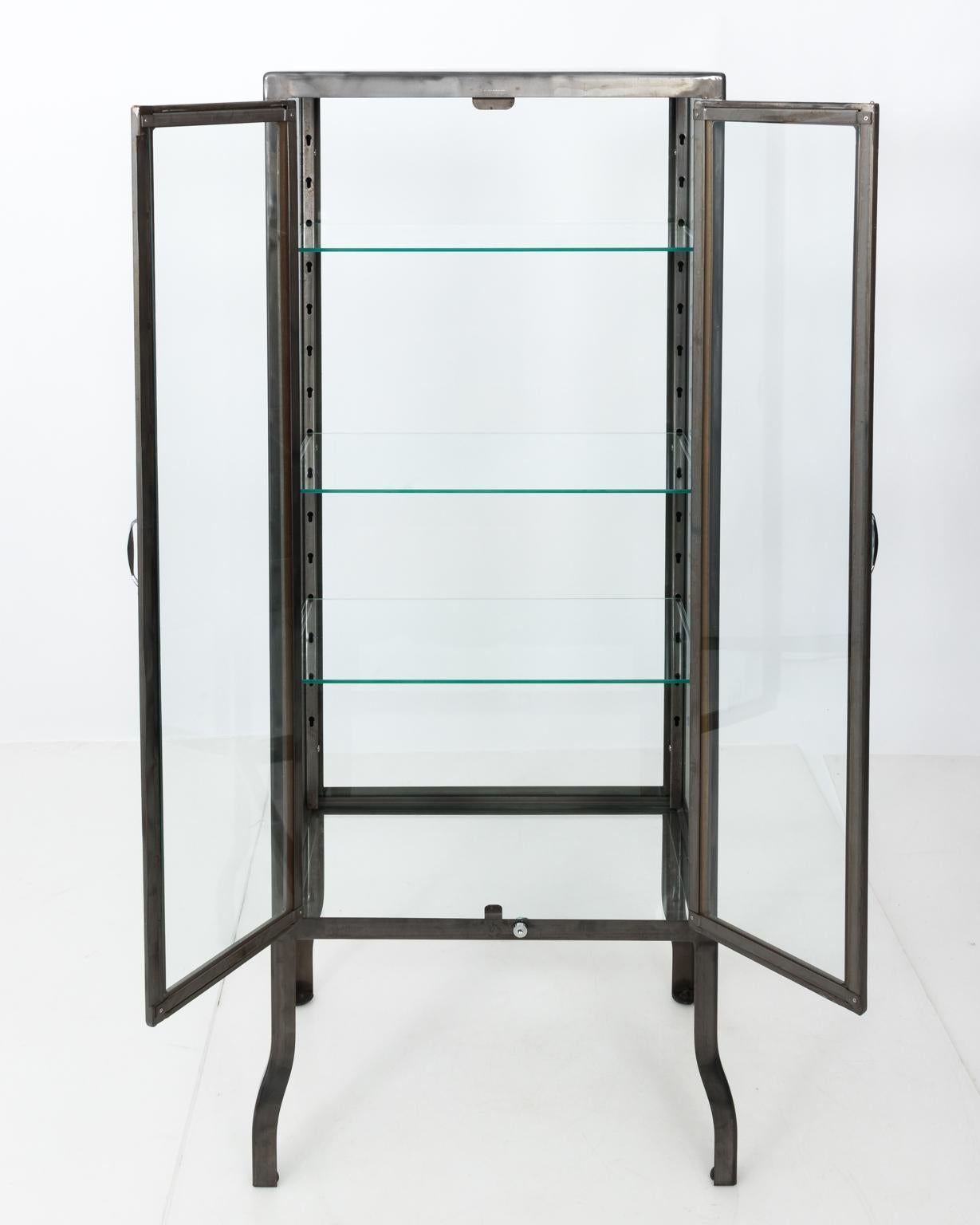 Industrial lacquered steel and glass apothecary cabinet with two doors and three adjustable glass shelves. Ideal as a display cabinet, in a bathroom, or as a bar.
  