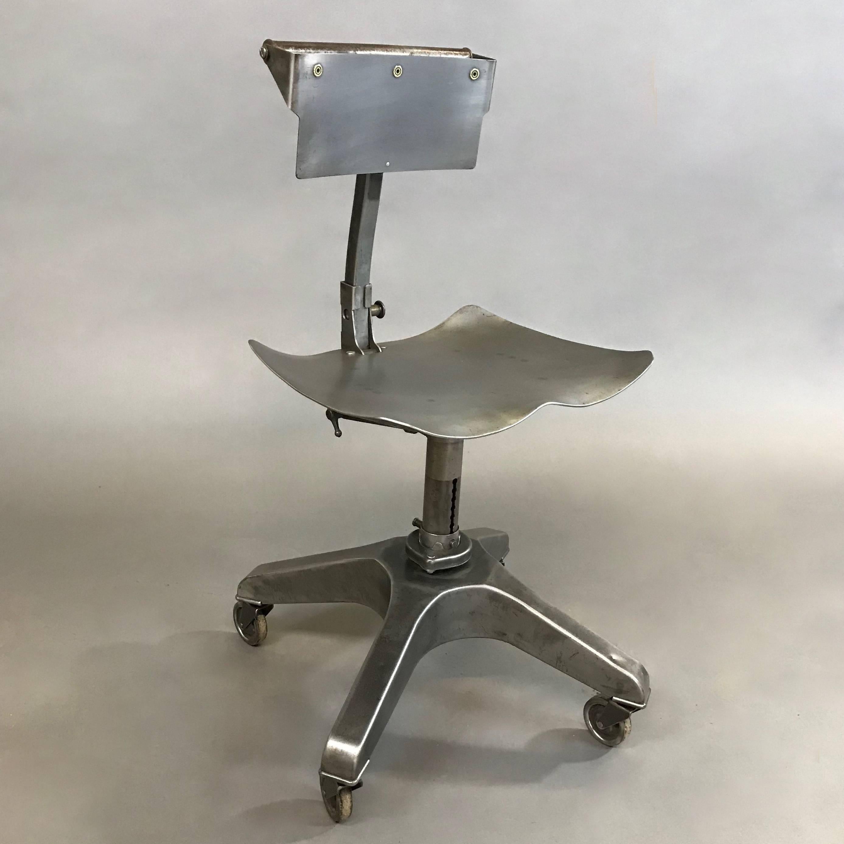 Industrial, brushed heavy gauge steel, adjustable posture office chair or stool designed by Ernest Bacz and manufactured by the Burroughs Adding Machine Company of Detroit, features a contoured saddle seat with telescopic pedestal base that adjusts