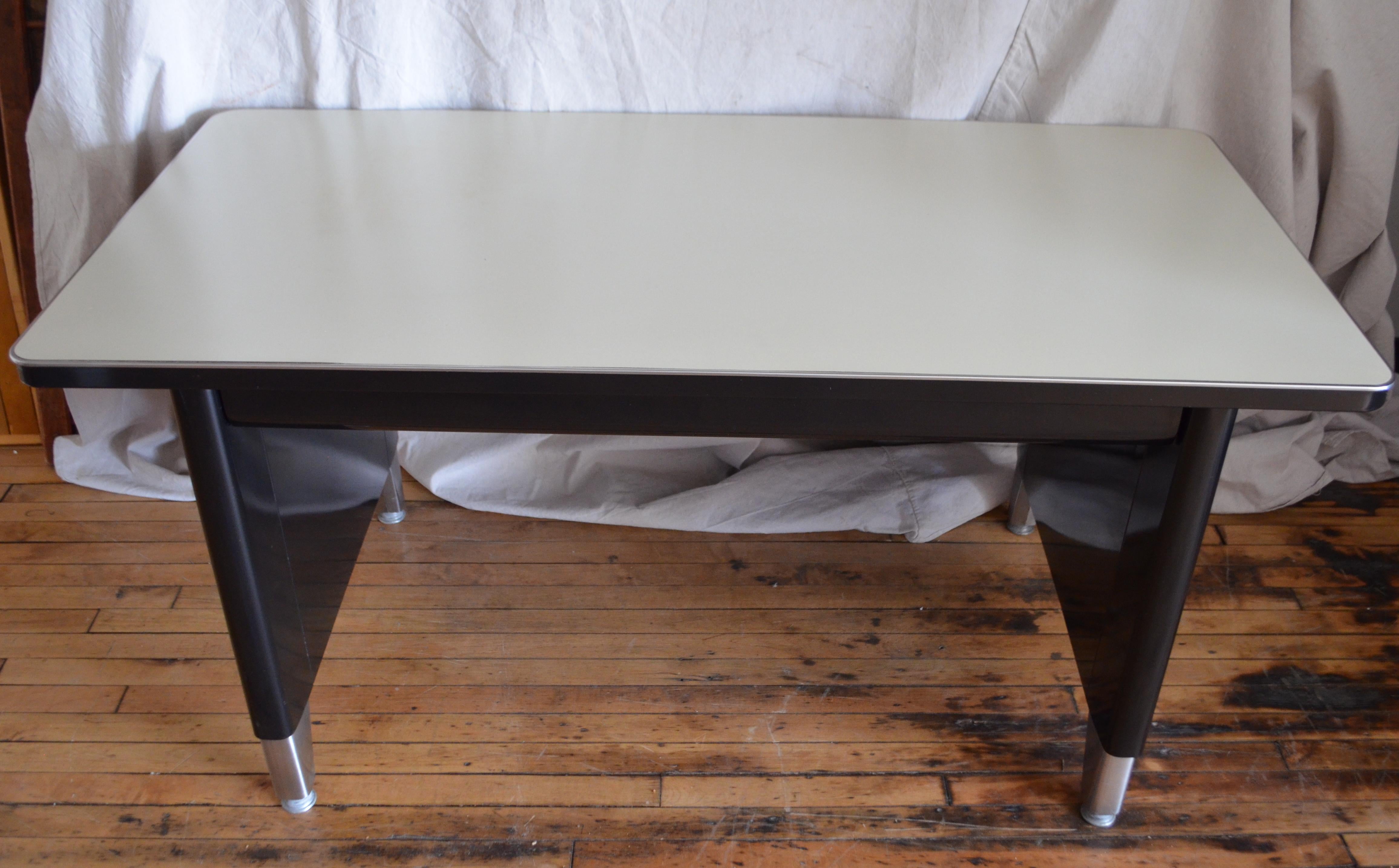 Industrial steel desk. Invincible brand. Painted black steel frame, creamy off-white laminate top and chrome feet. In extraordinary condition. A midcentury icon. The Boomers grew up with them. They were a fundamental fixture in every office. This