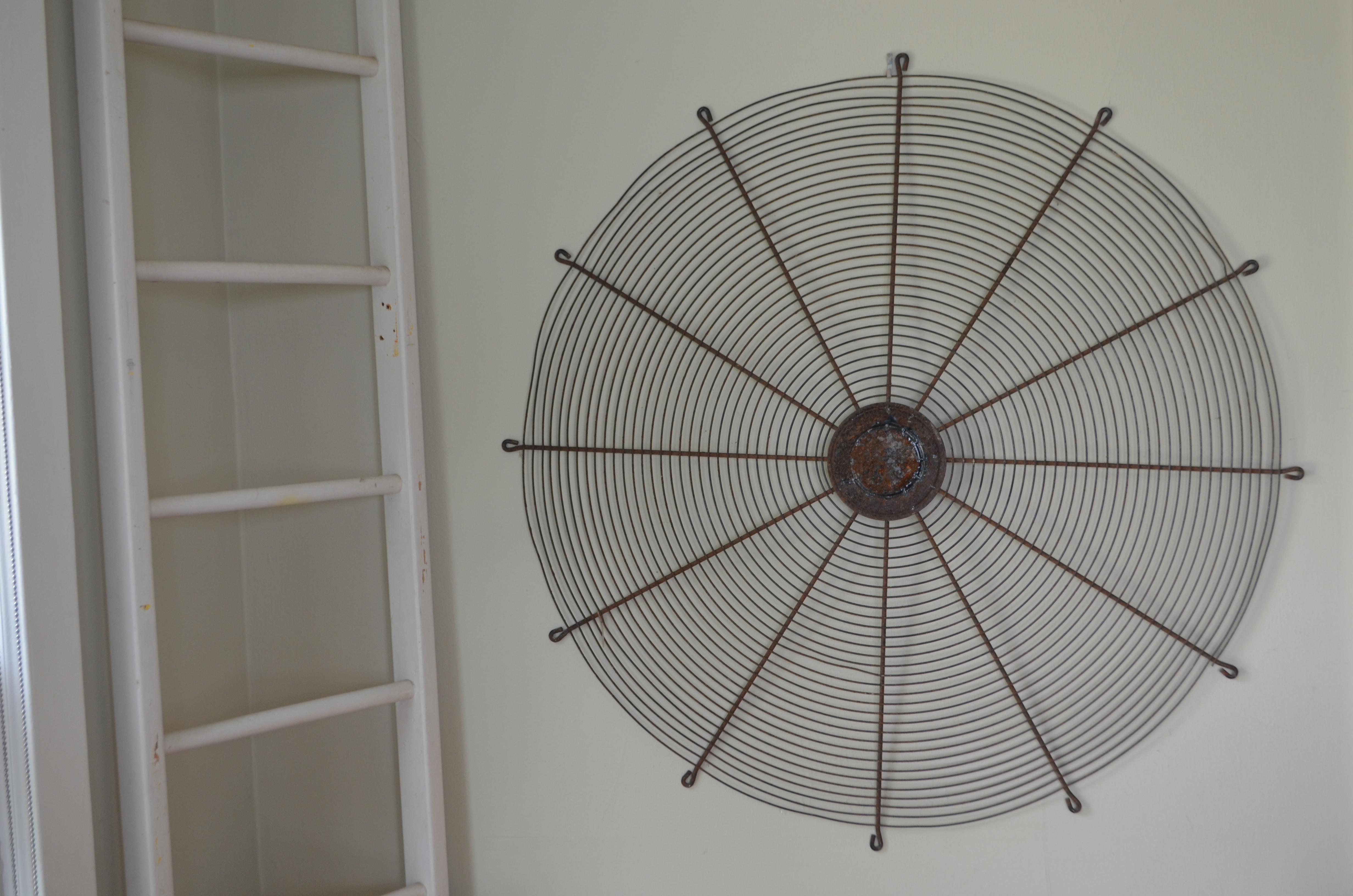 Industrial steel fan cover from midcentury factory as dramatic wall art at 4-ft diameter. Spider web-like in its structure and simplicity. Tactile patina of light rust from age and use. Uniquely eye-catching and, at the same time, soothing to behold.