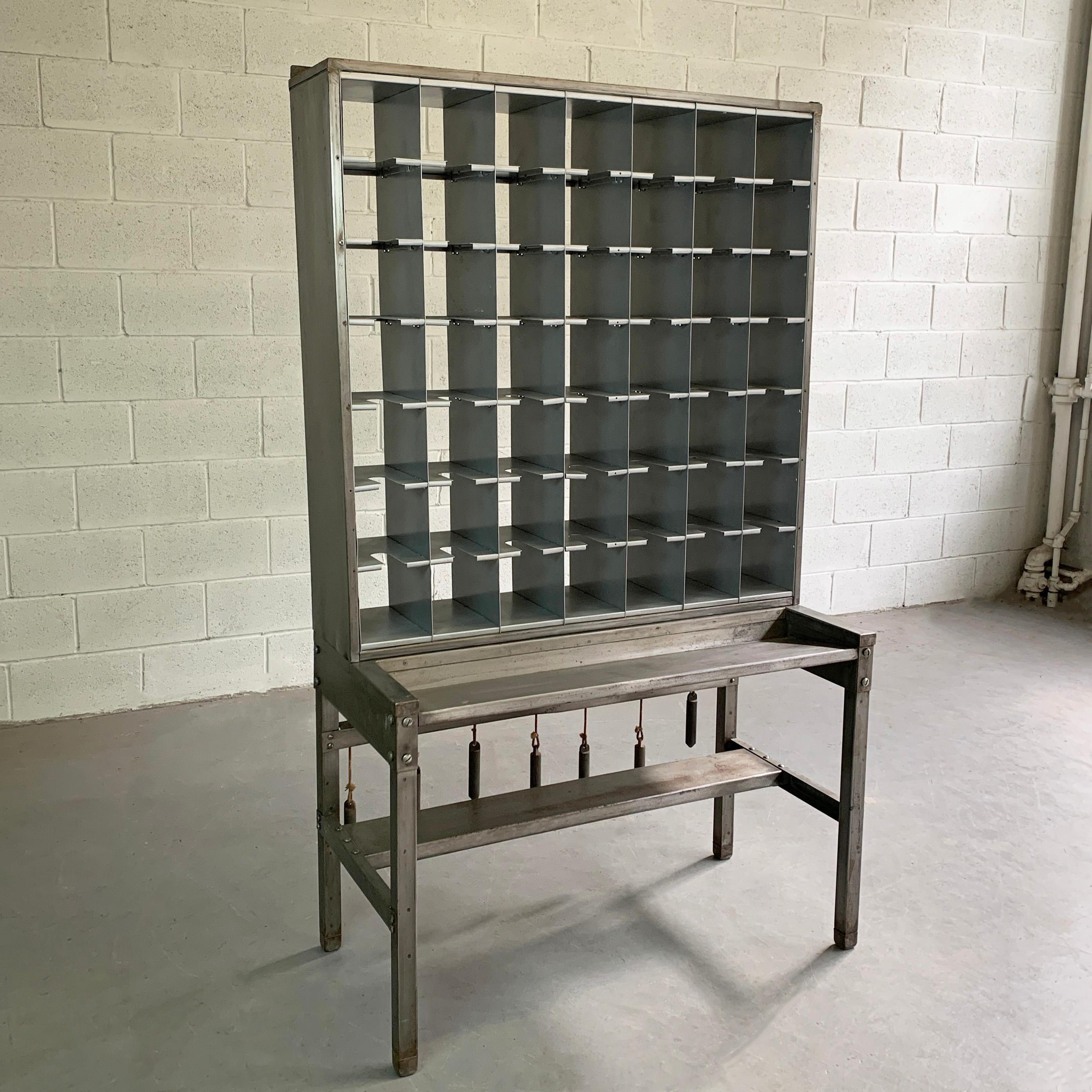 Midcentury, industrial, steel, mail sorter unit features 49, 6 x 6 x 10 inch deep cubby hole, mail slots, work ledge at 27 inches height and tension ropes with weights in the back that aids in placing the mail in at the time of sorting. The lower