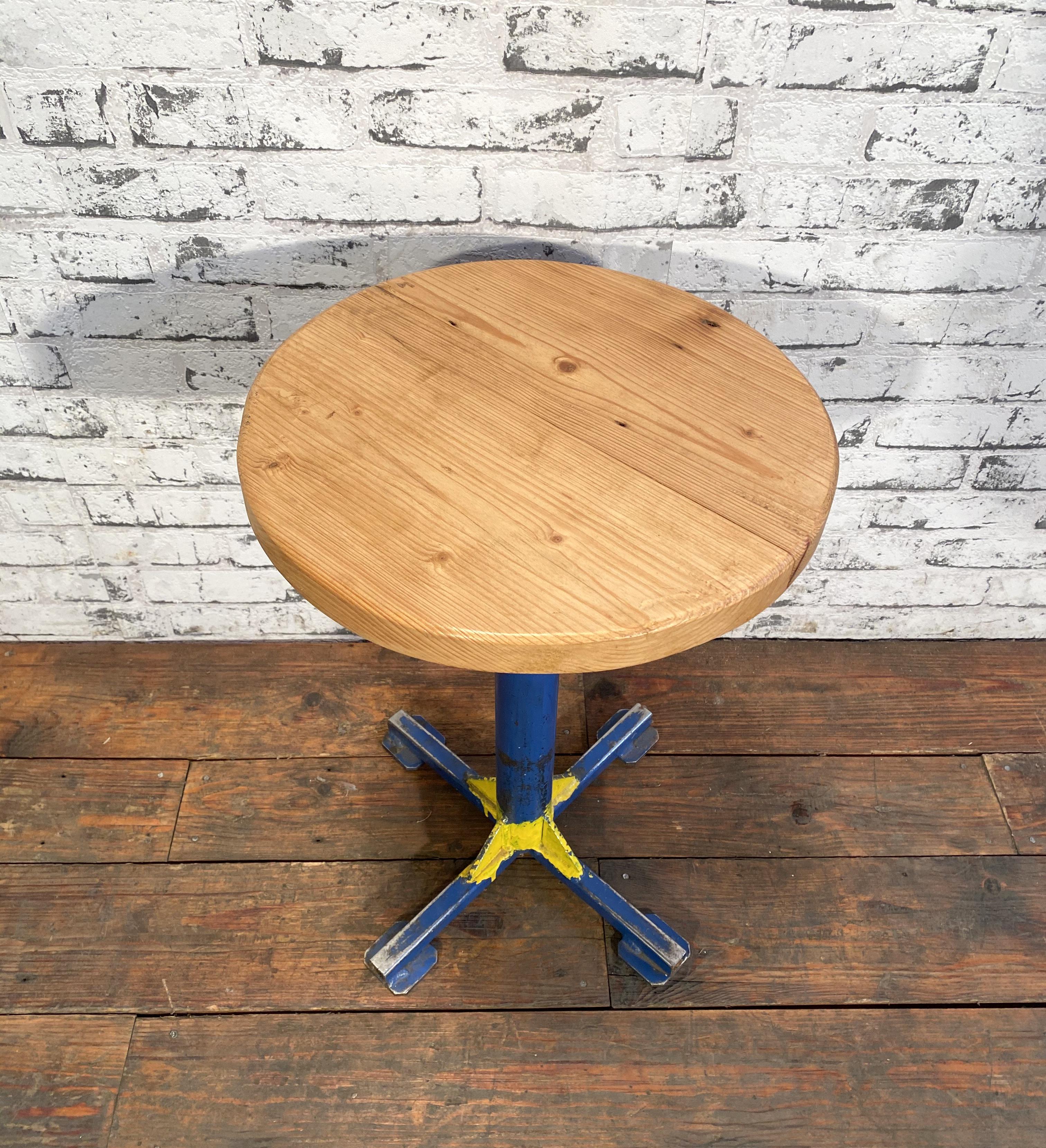 Vintage industrial stool. It features a blue iron leg and a solid wooden seat.