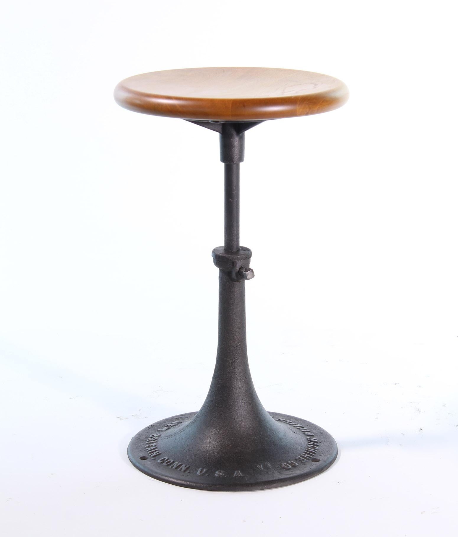 Authentic antique wood and cast iron backless industrial adjustable factory stool made by The New Britain Machine Company of Connecticut. The seat diameter measures 12 7/8