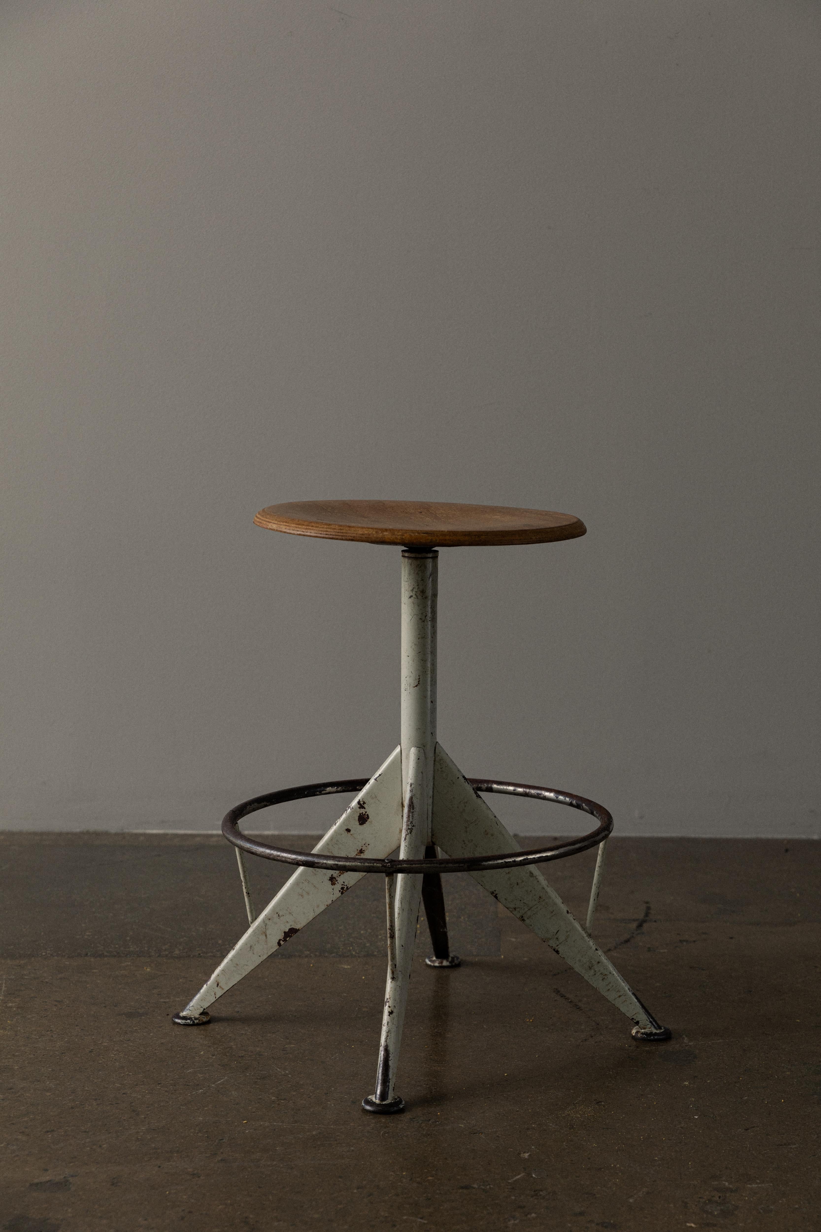 The stool features a sturdy metal frame in a sleek and minimalist design, typical of mid-century industrial furniture. The swivel mechanism allows for easy movement and adjustability, adding a touch of functionality to the piece. This is a timeless