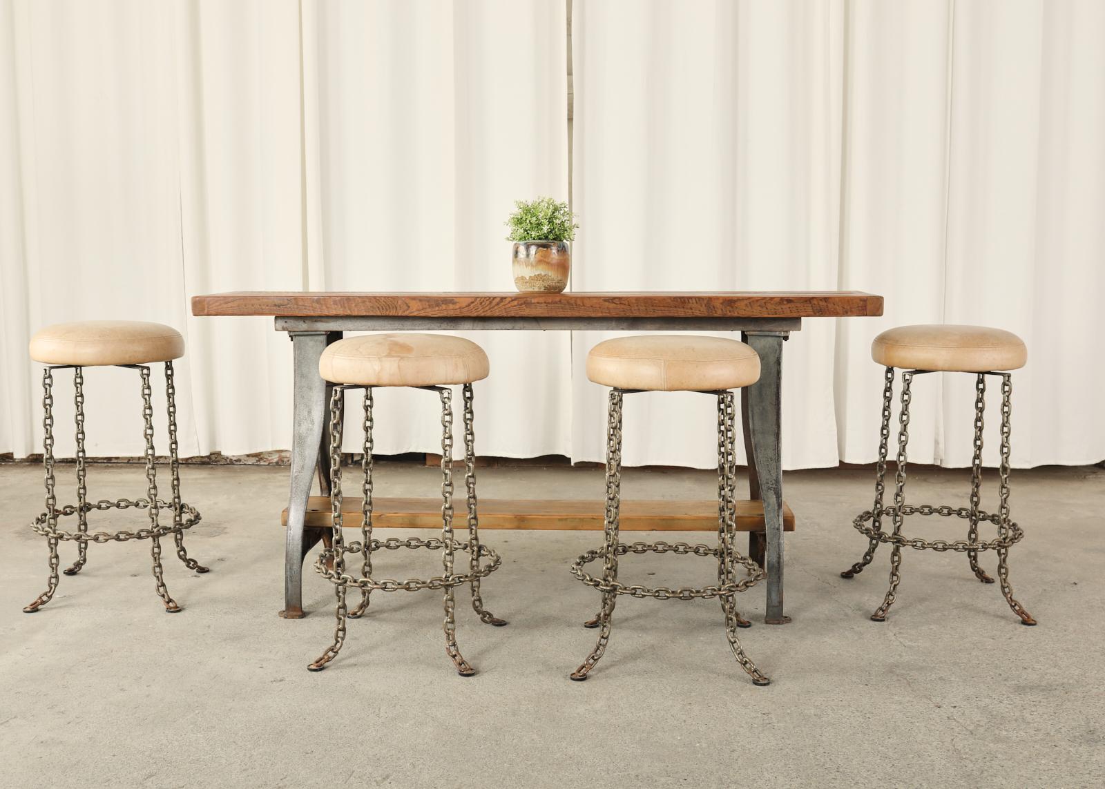 Early American industrial style work table or console table featuring factory cast iron legs. The trestle style table is topped with a 2 inch thick slab of plank board having breadboard ends. Supported by gracefully shaped legs that conjoin with a