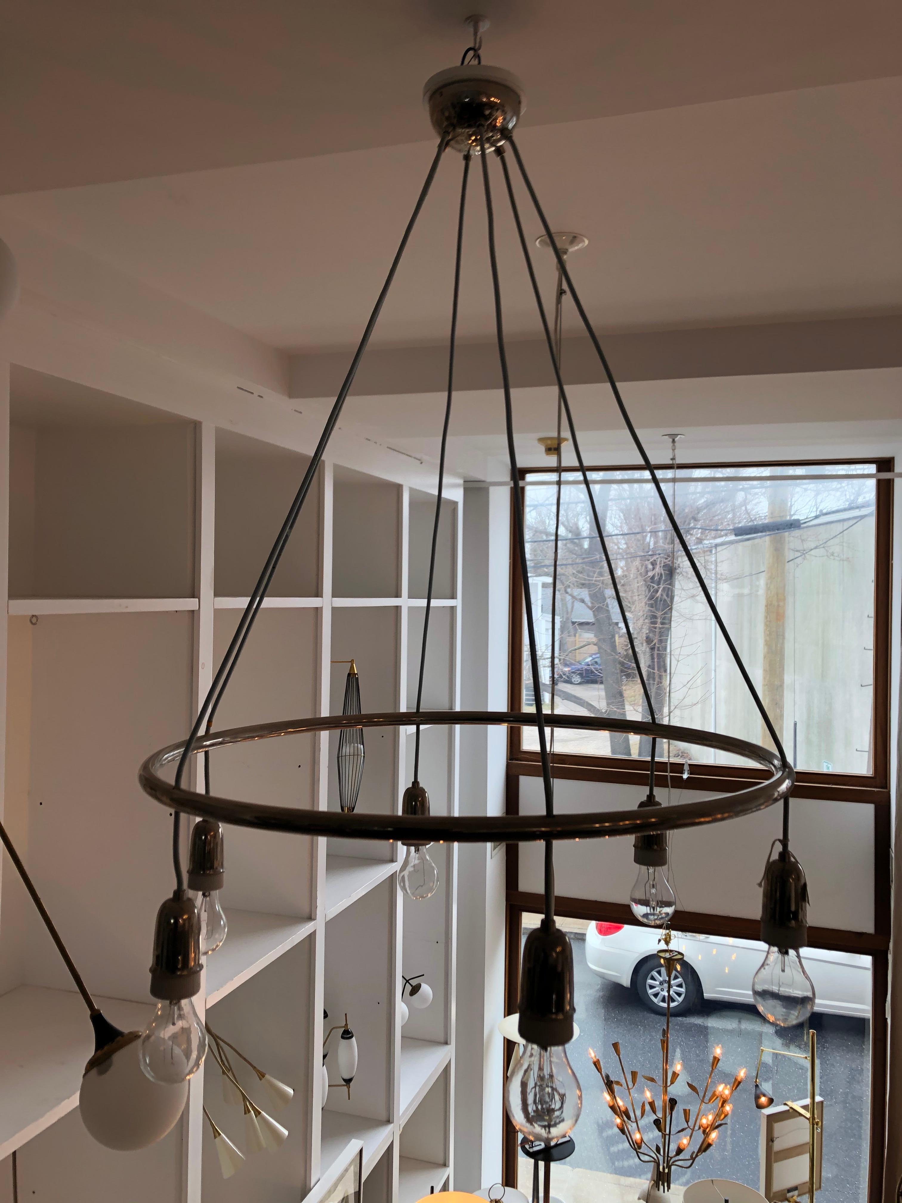 This unusual chandelier is suspended from the chrome canopy with six lines to a circular chrome tubular element from which the exposed filament bulbs are hung. Overall height is 41/42