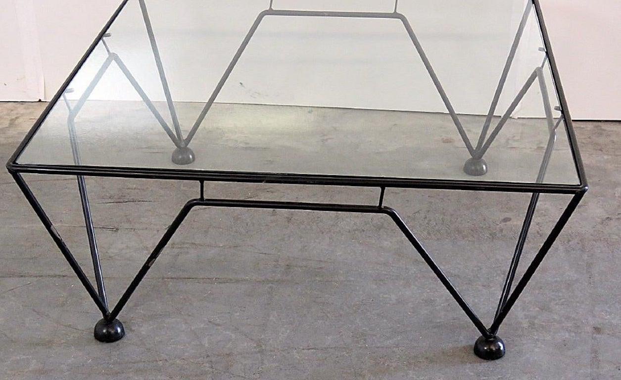 An iron coffee table in the style of Italian Industrial designer Paolo Piva. Geometric design with connecting angular supports terminating on ball feet with a glass top. 
Dimensions: 15 1/2