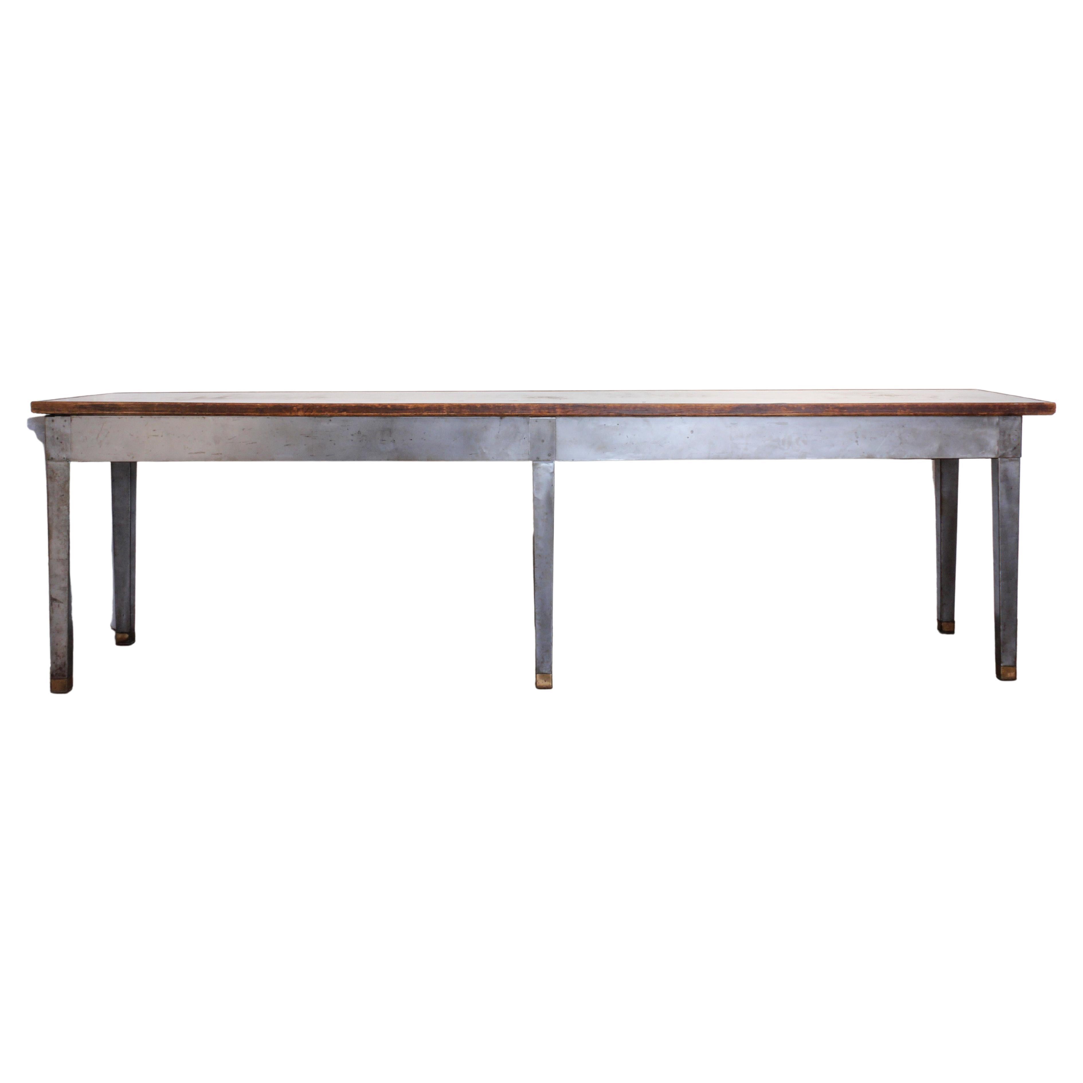 Vintage 20th century industrial style long steel console table with brass sabots and a wood frame around the steel top. Six (6) legs, very sturdy.