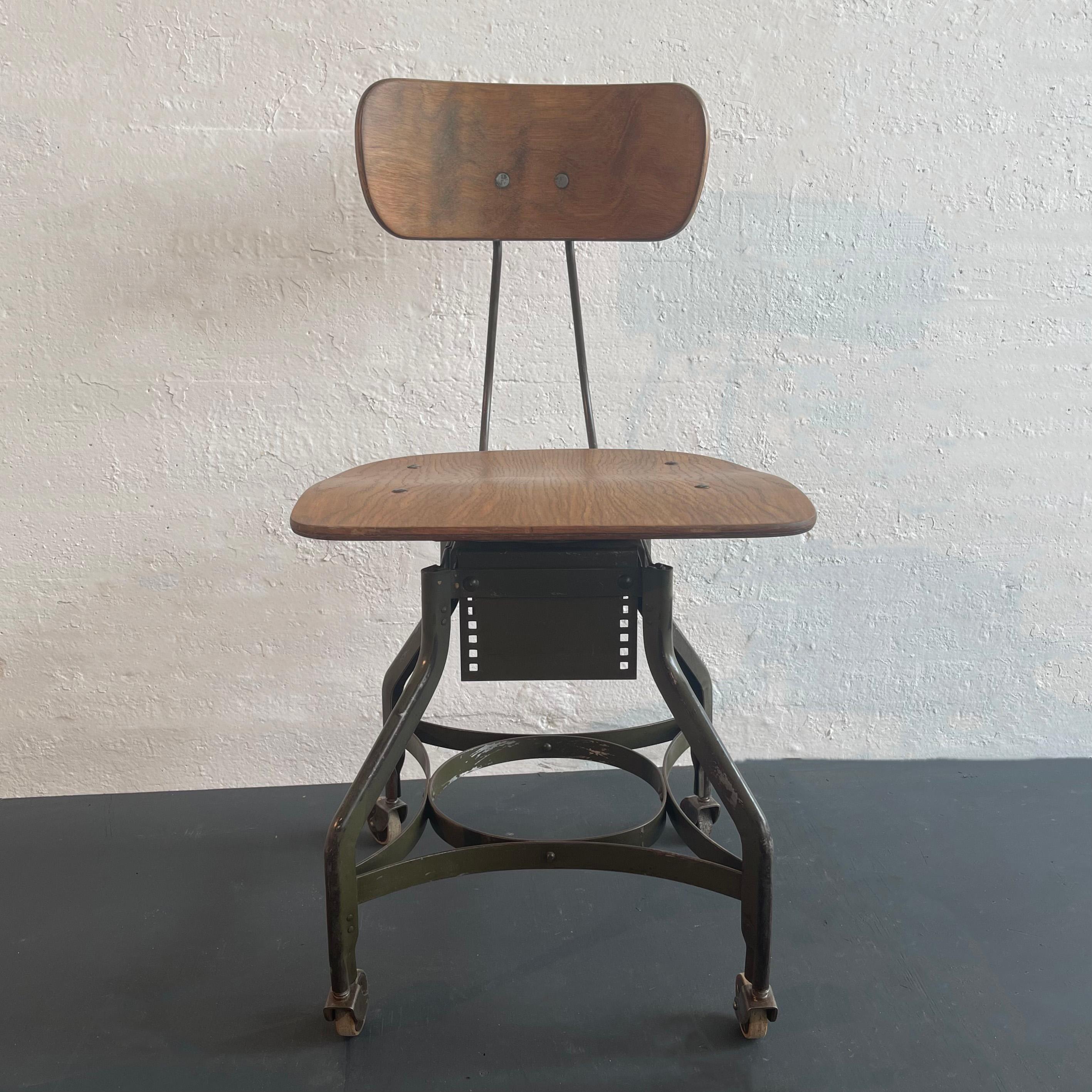 Industrial, adjustable, swivel side chair by Toledo Metal Furniture Co. features the signature Toledo star painted steel base that rolls on casters with bent maple seat and back. The height is adjustable from 18 - 21 inches by setting the plate