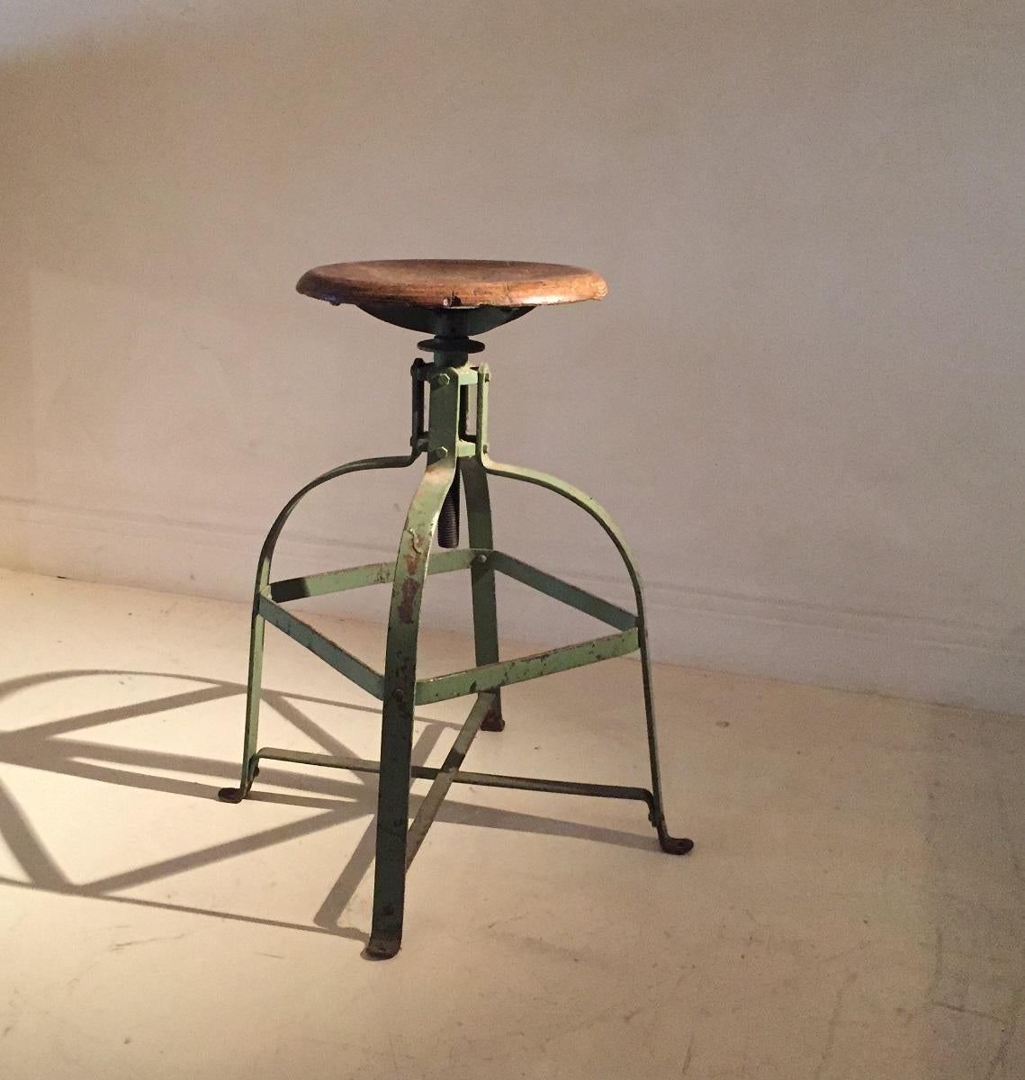 1930s industrial swivel stool. The adjustable beech sit has a nice patina as well as the green paint remains on the iron supports. The height mechanism functions as new and the structure is very solid. The seat can be raised circa 10 cm's or 4