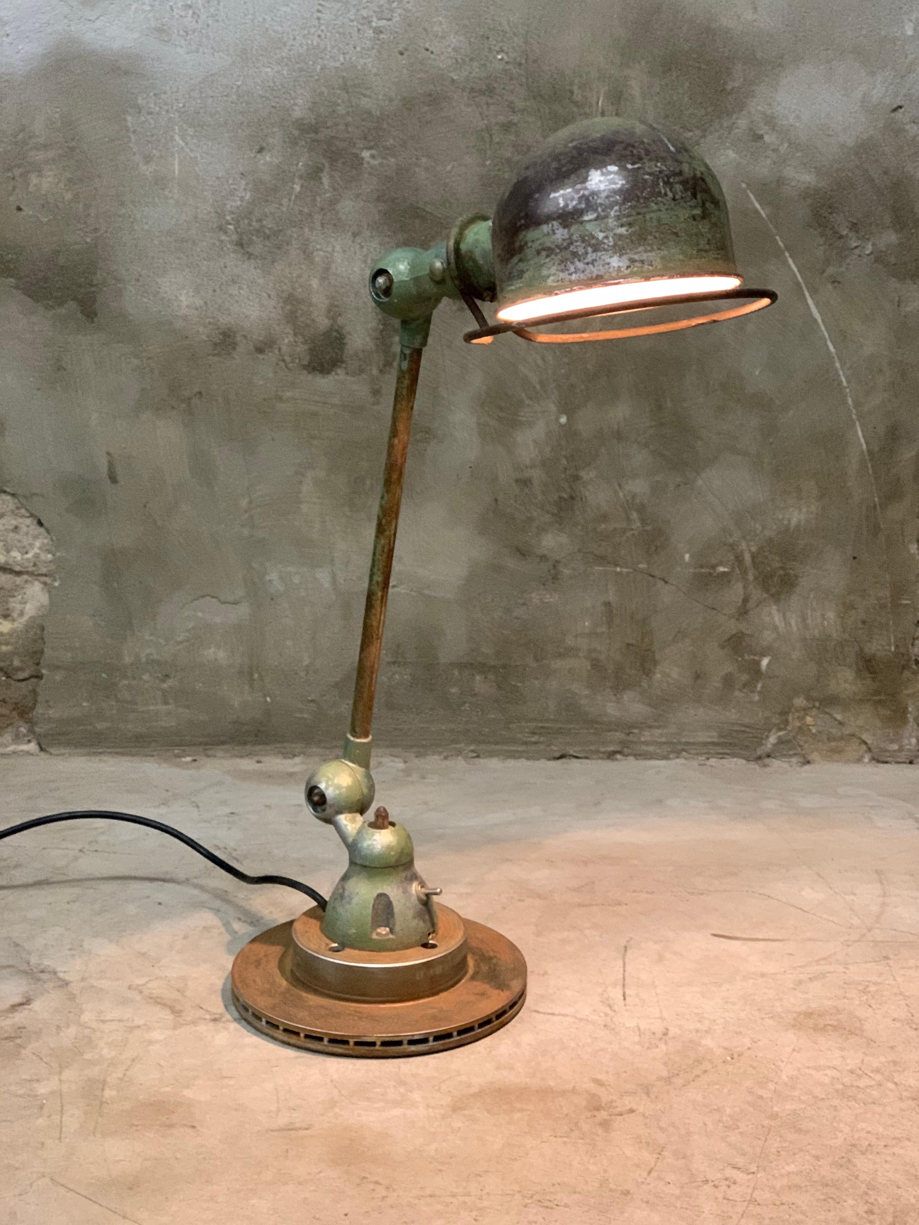 Industrial lamp by Jean-Louis Domecq for Jieldé, France, 1960s. This original old Jieldé table lamp has a fantastic patina! Bayonet lamp fitting including lamp (can still be ordered if it breaks). Placed on an old brake disc. 

Flip switch in the