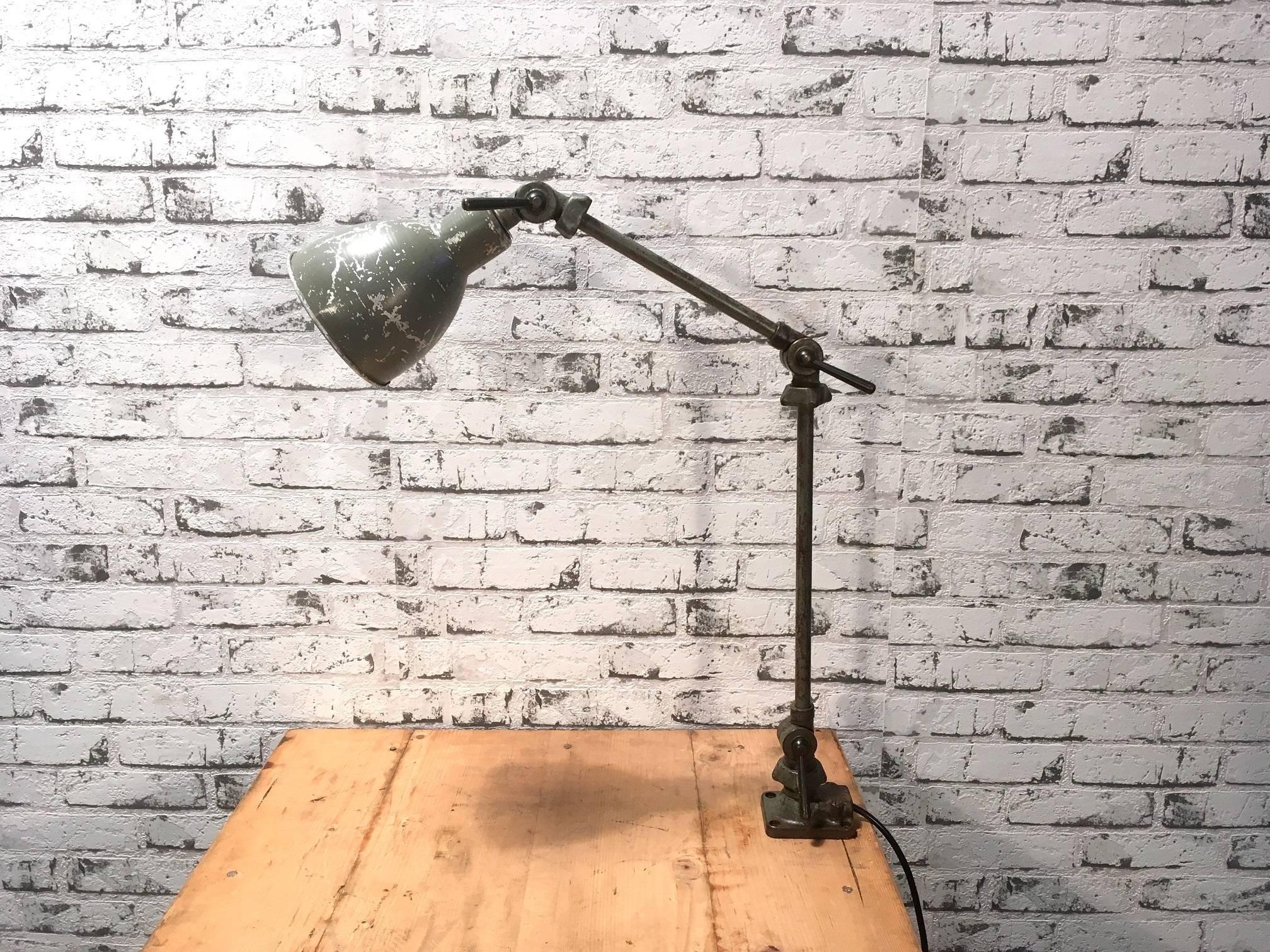 Industrial table lamp from the 1930s. It features an iron base, an iron arm with three adjustable joints and aluminium shade. The socket requires E 27 lightbulb. New wiring.The diameter of the shade is 12 cm.
 