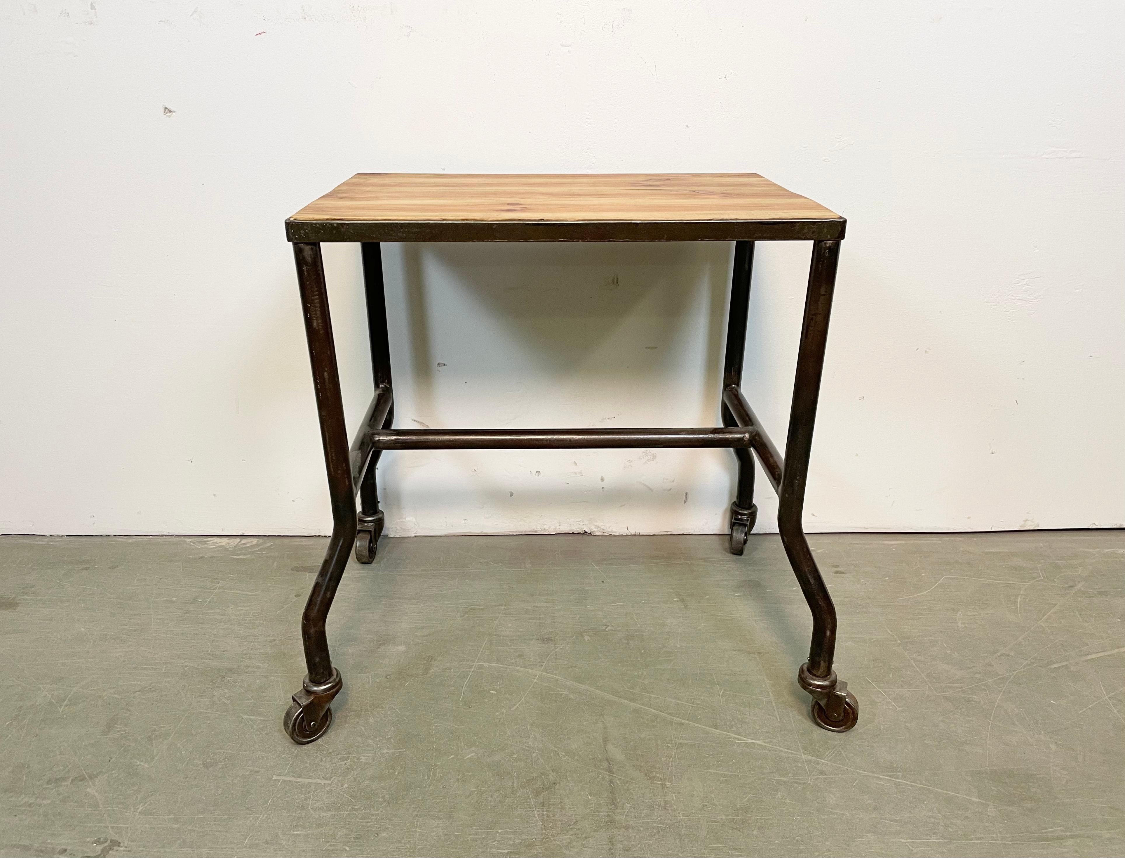 Industrial table from the 1960s. It features an iron construction,a four original wheels and a solid wooden plate. The weight of the table is 7 kg.