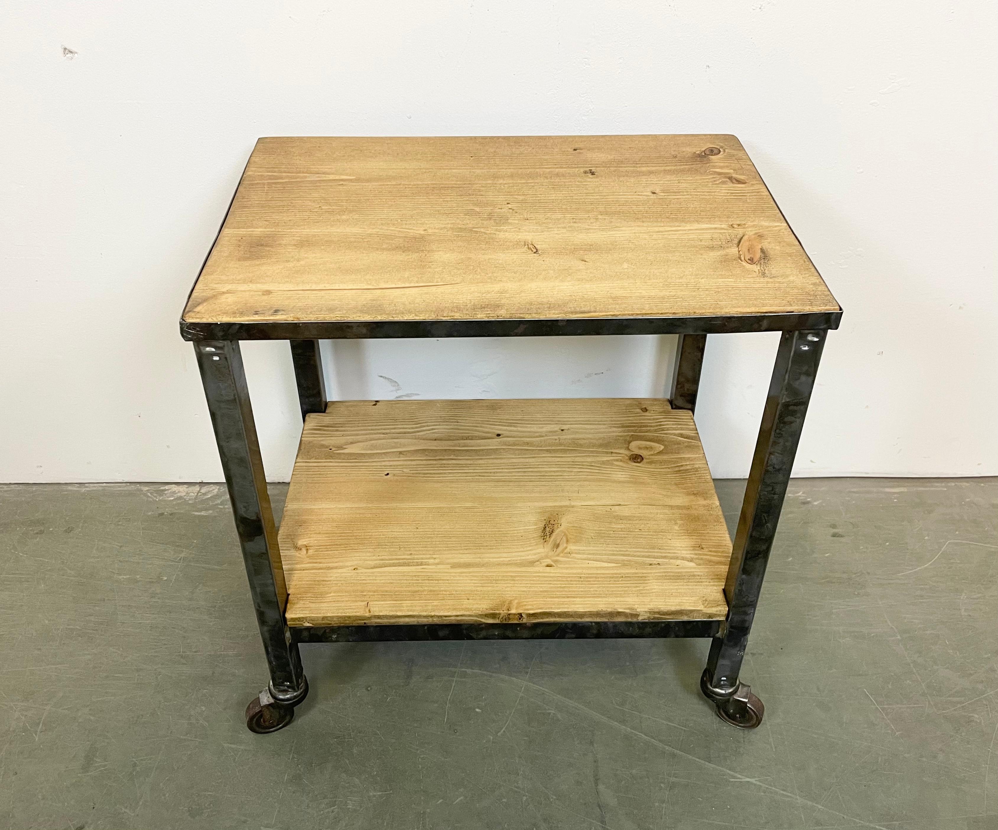 Industrial table from the 1960s. It features an iron construction,a four original wheels and a solid wooden plate. The weight of the table is 7 kg.