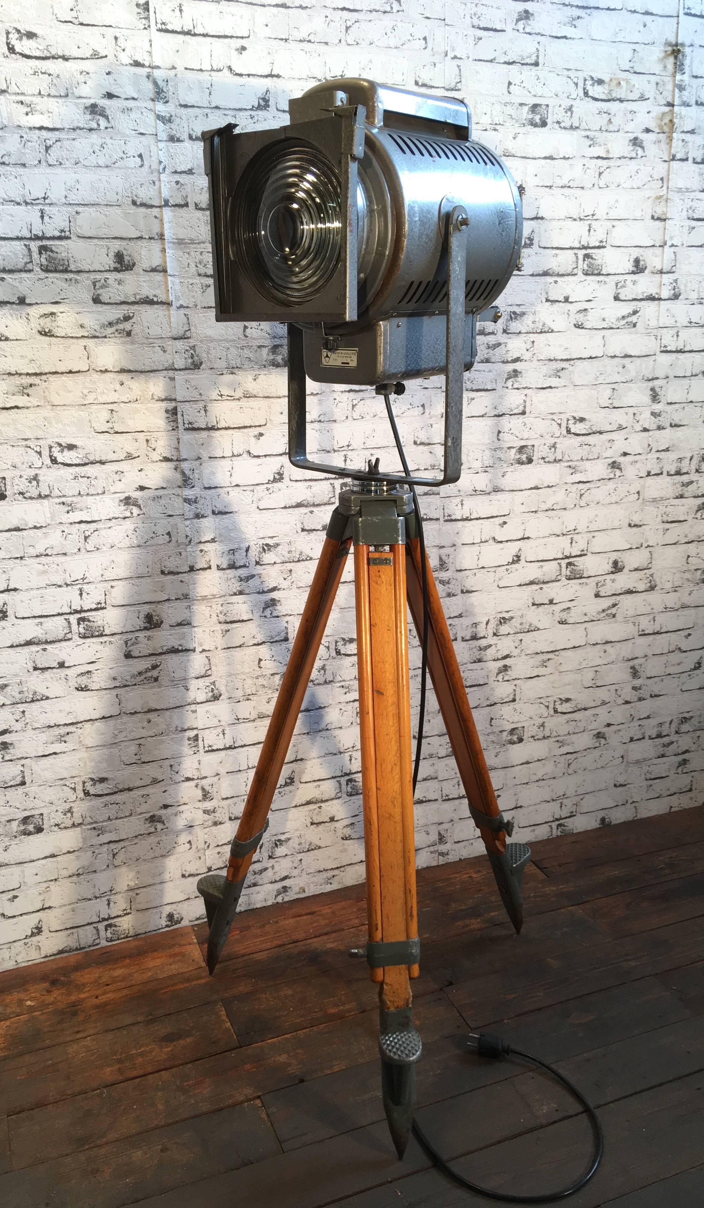 Industrial Russian spotlight on wooden tripod. Adjustable height and angle. Grey metal body. Clear glass. Measures: Min. total height 150 cm, Max. total height 200 cm. New porcelain socket E27.New wire. Very good vintage condition,
weight 25kg.