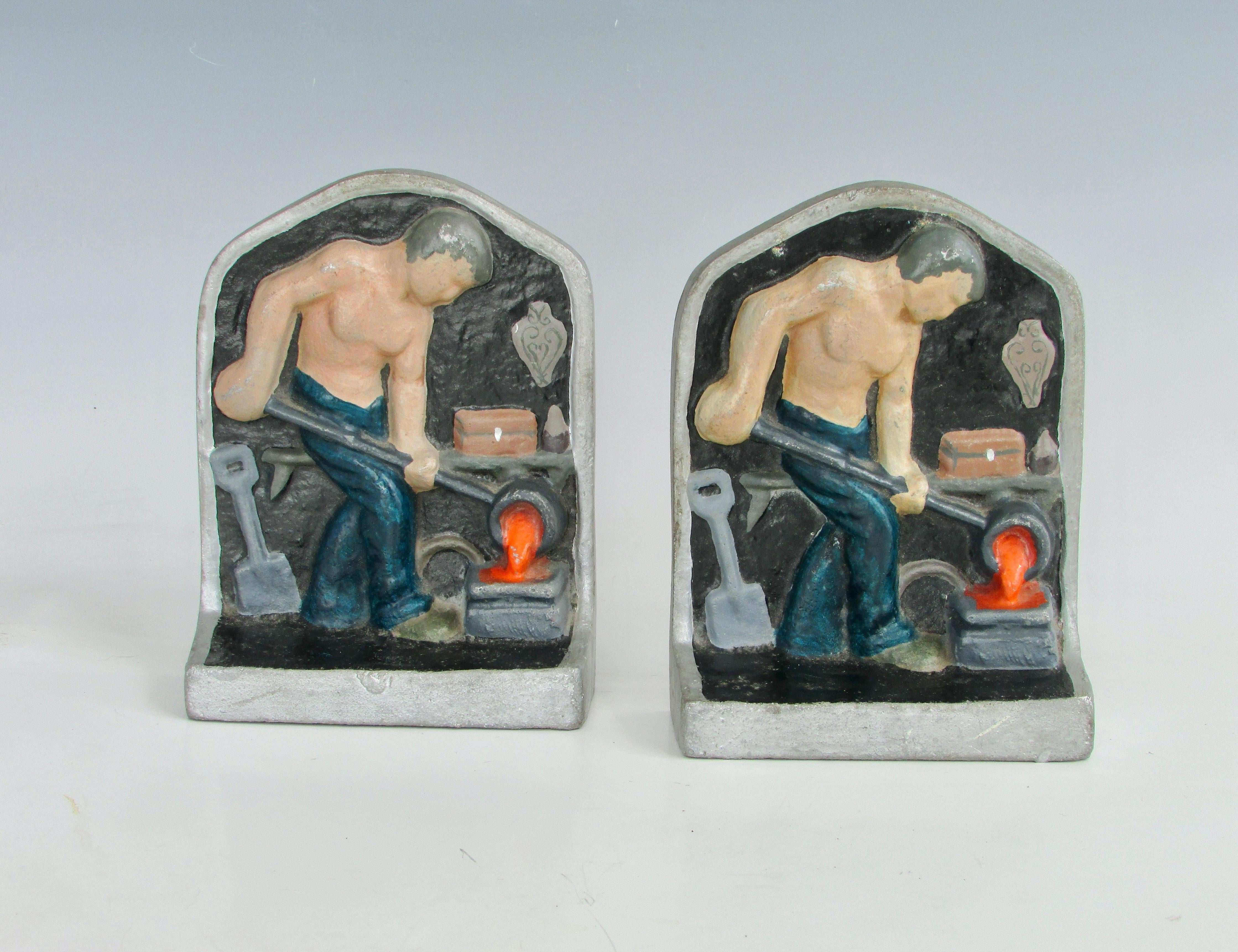 Pair of industrial themed cast aluminum bookends. Both pieces depict bare chested man in a forge setting pouring molten metal from crucible into a mold.
