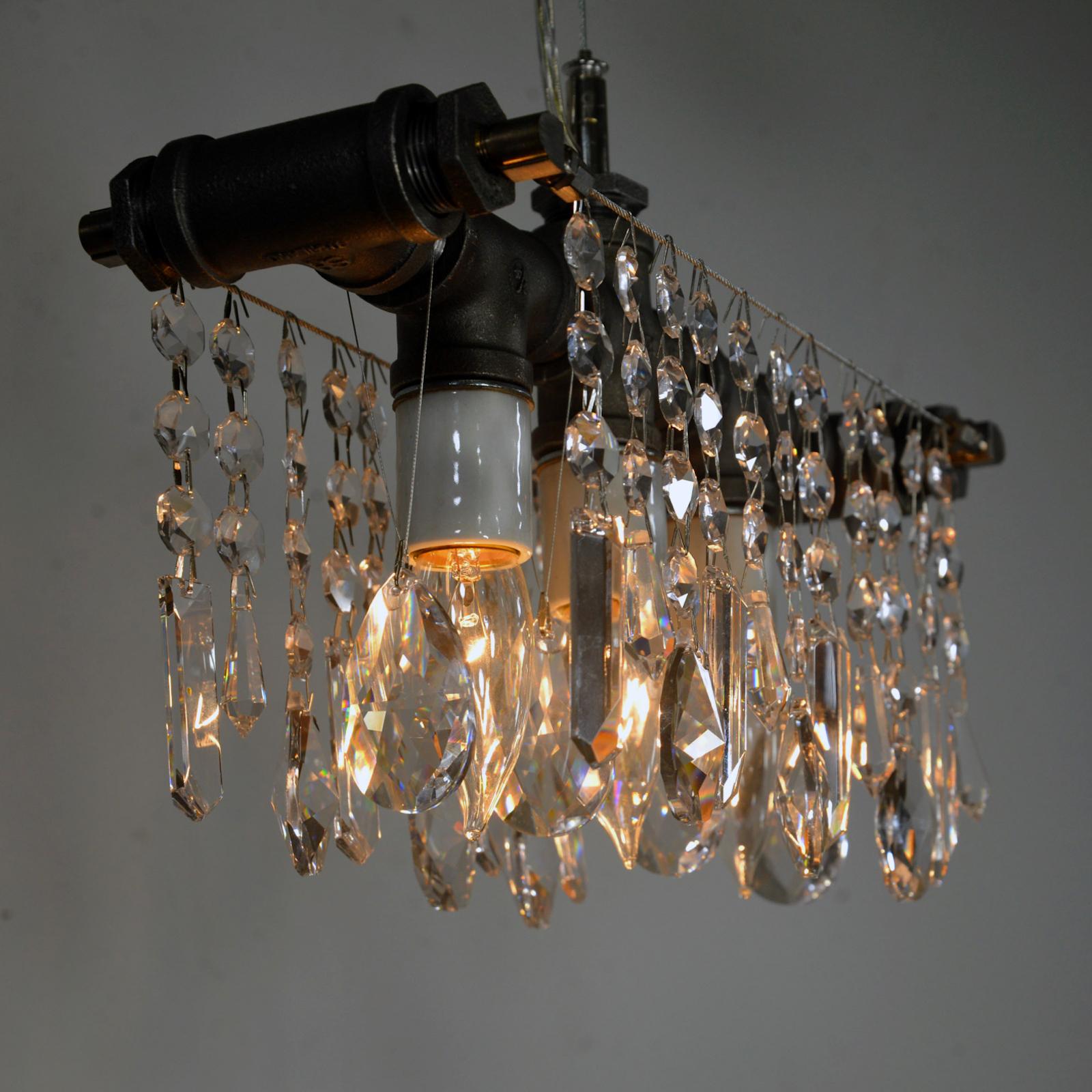 The industrial three bulb chandelier is a crystal lighting fixture that may be small but has an oversized personality. It gets the Michael McHale Designs formula of polished European crystals contrasting with rough industrial elements exactly right.