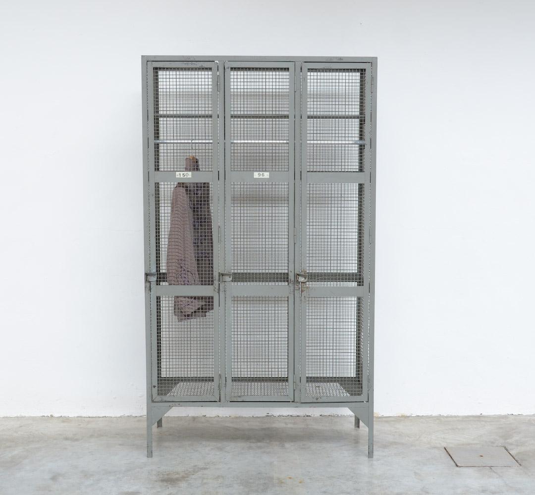 This great old Industrial locker wardrobe cabinet can be dated in the 1950s.
With its metal fence side panels and doors in grey lacquered metal, it stays transparent.
This three doors wardrobe is in very good industrial condition, of course