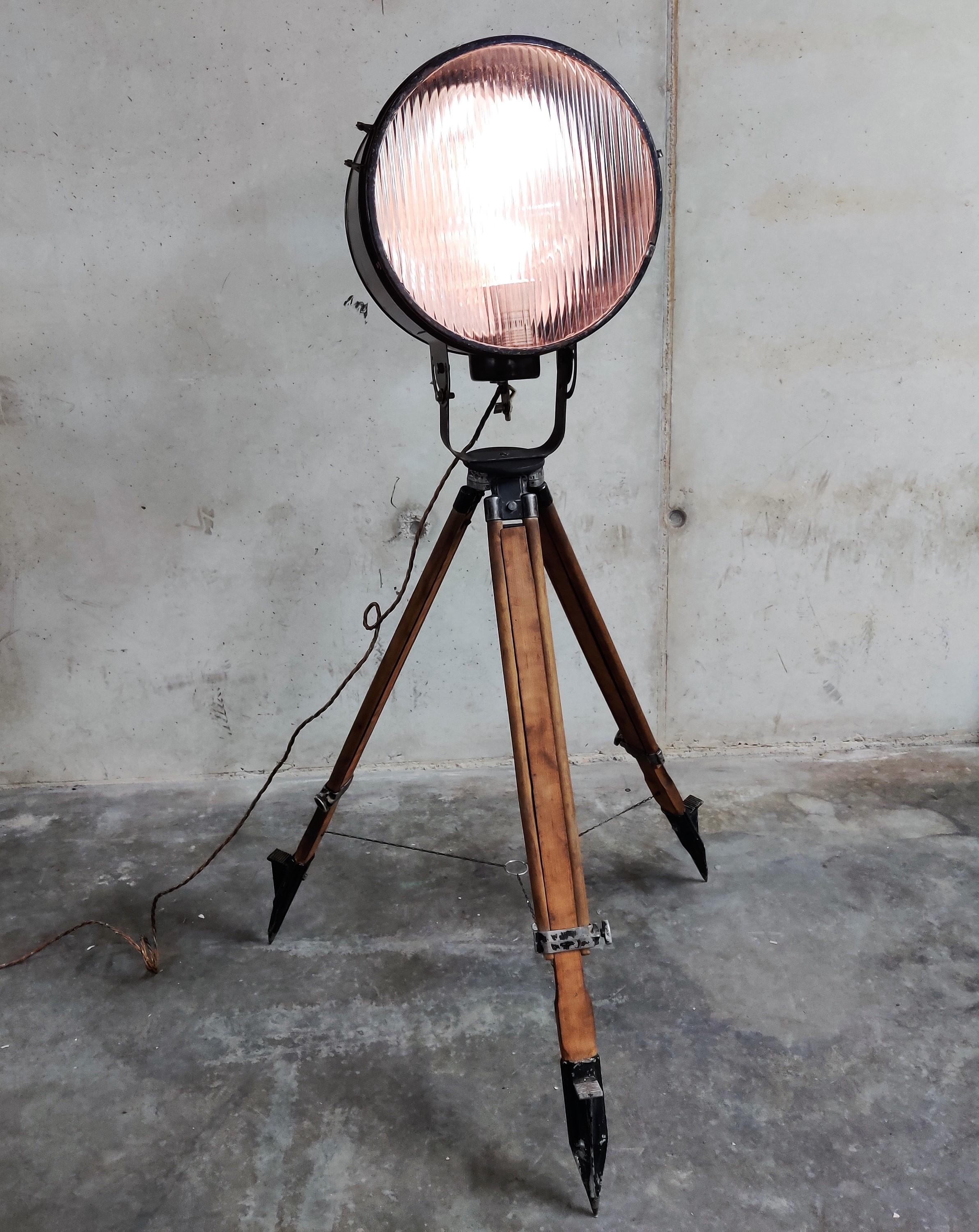 Wonderful industrial spotlight, coming from a ship.

The light has a reflector on the inside and ribbled glass, creating a diffuse light.

The lamp is mounted on a vintage wooden tripod, adjustable in height.

This floor lamp is a real eye