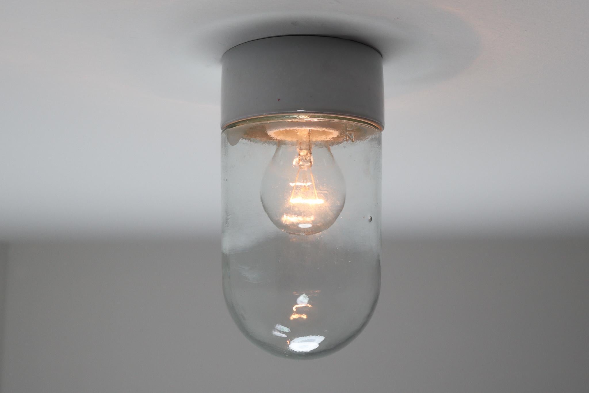 Small industrial vintage modern wall/ceiling lights with clear glass and porcelain base, France, 1960s. Good original condition. Fitted with a porcelain E27 socket. The lights are compatible with the US/UK/ etc., standards. Also LED compatible. 2