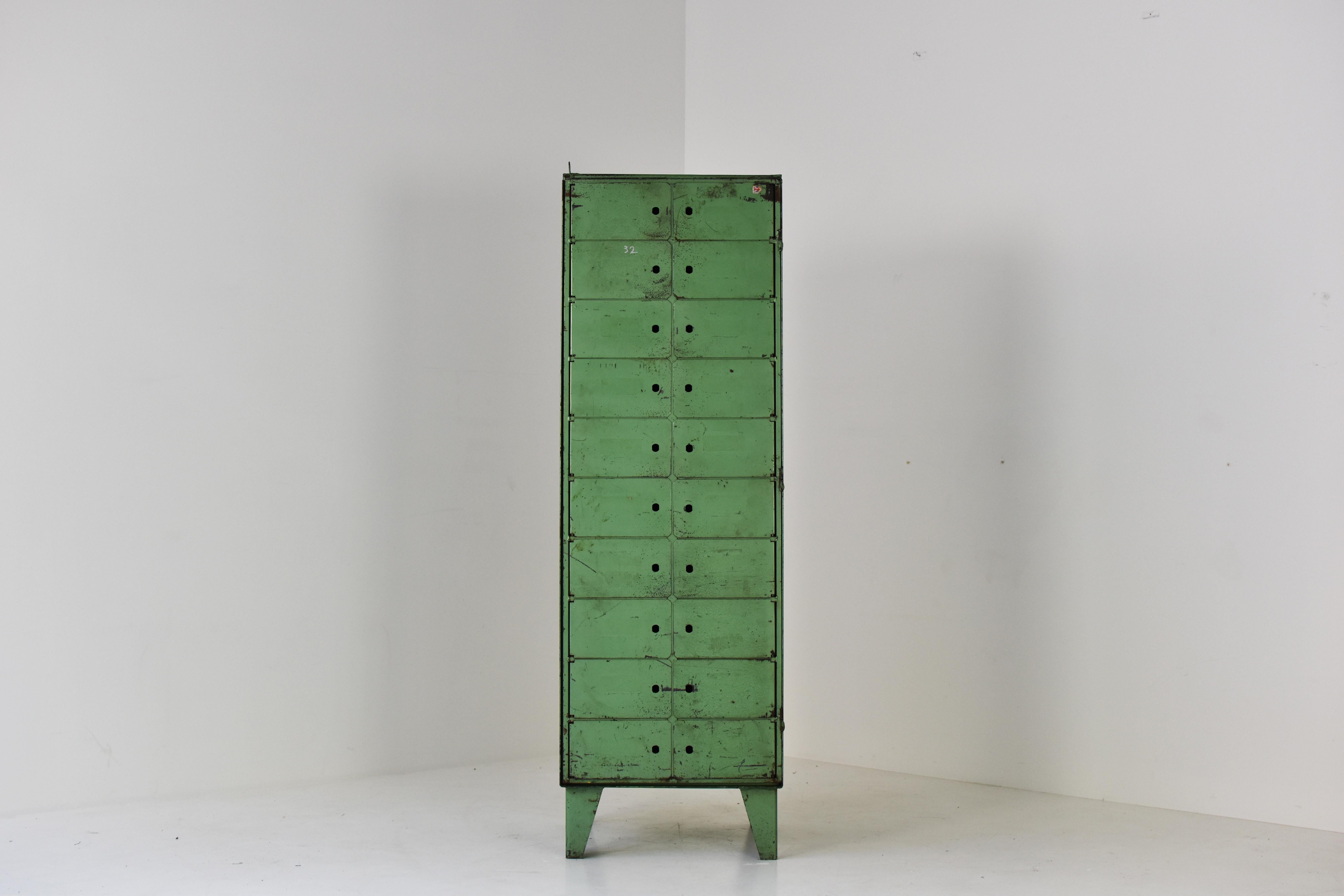 Industrial vitrine cabinet dating from the 1930s, probably from the U.K. This locker has multiple little doors to individually open the storage area behind, or one central door for open them all. Lovely green lacquer which has been aged beautifully.