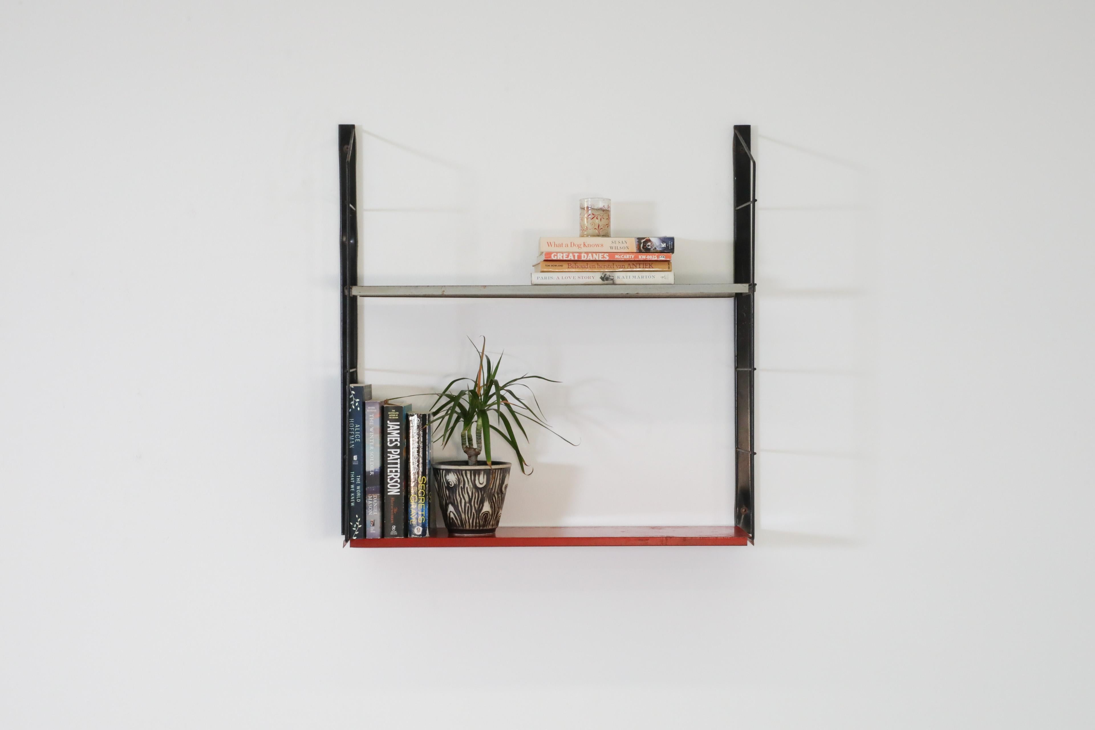 Dutch Mid-Century, single section wall mounted Tomado style industrial shelving unit with gray and red metal shelves on black wire risers. Has the added feature that the unit can be used in a slightly wider configuration depending on how you mount
