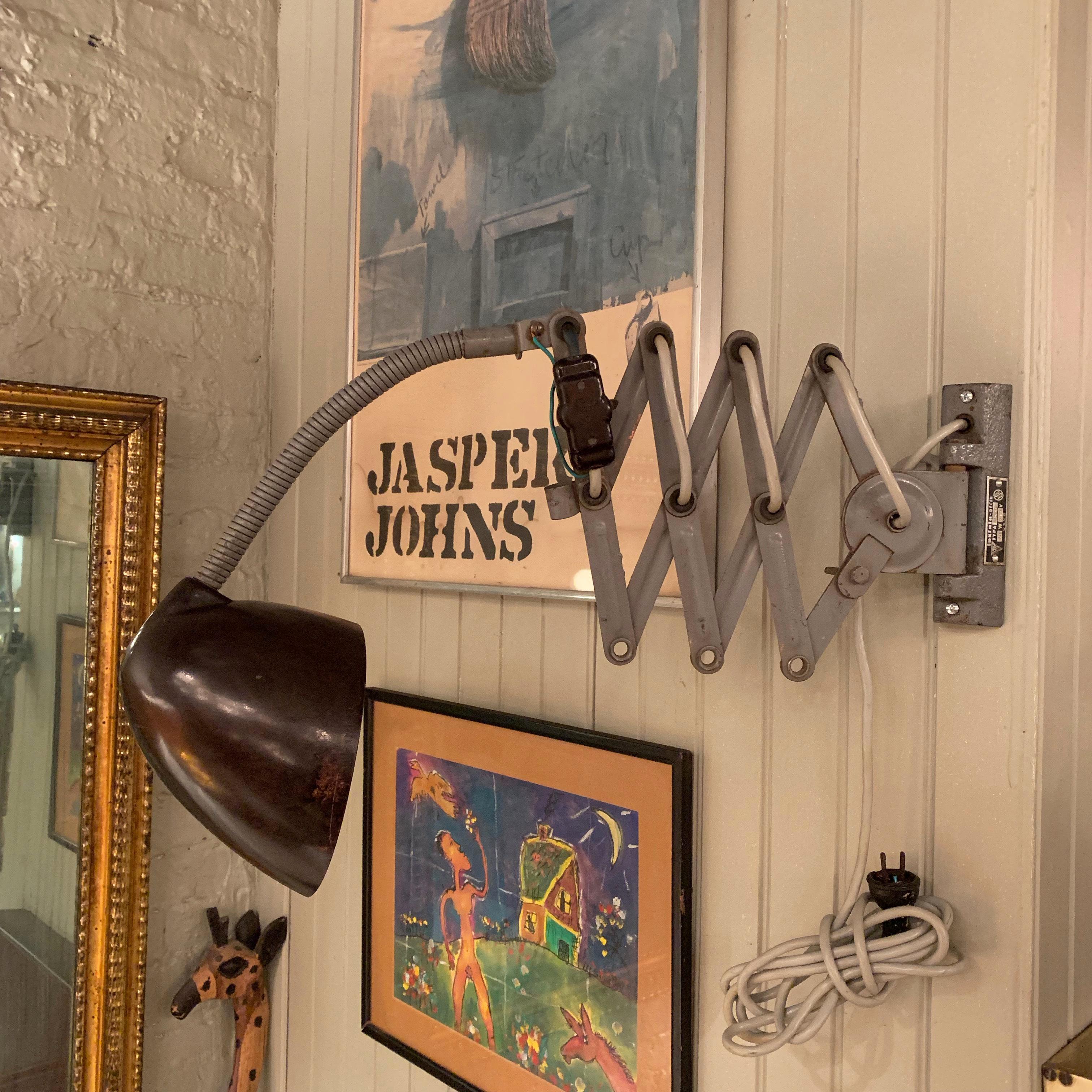Industrial, midcentury, West German, task lamp, wall sconce features a cast iron mount plate with adjustable, painted steel scissor and gooseneck. And shade and switch made of Catalin. The lamp stretches from 16 inches to 33 inches in depth and has