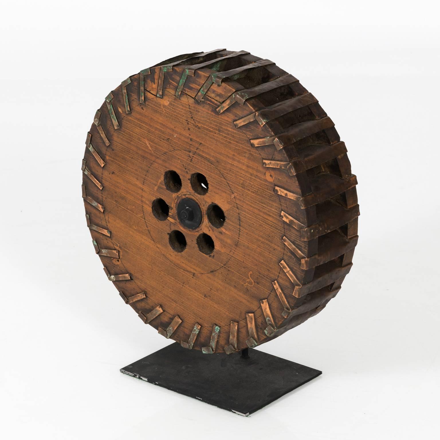 Contemporary Industrial wooden wheel sculpture on a metal base.
 