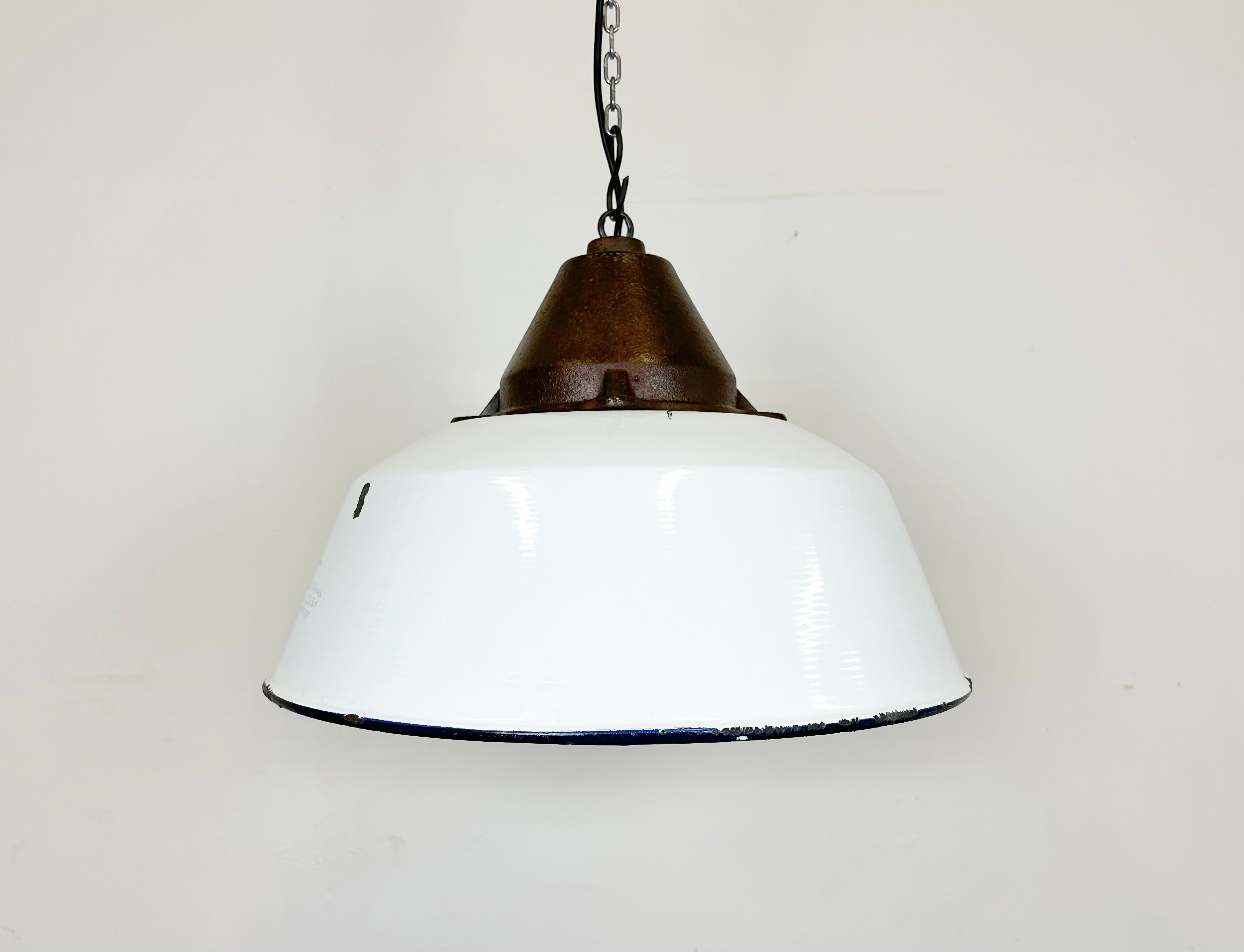 Industrial hanging lamp manufactured by Szarvasi Vas - Fém in Hungary during the 1960s. It features a white enamel shade, white enamel interior and a cast iron top. New porcelain socket requires E 27/ E26 light bulbs. New wire. The diameter of the