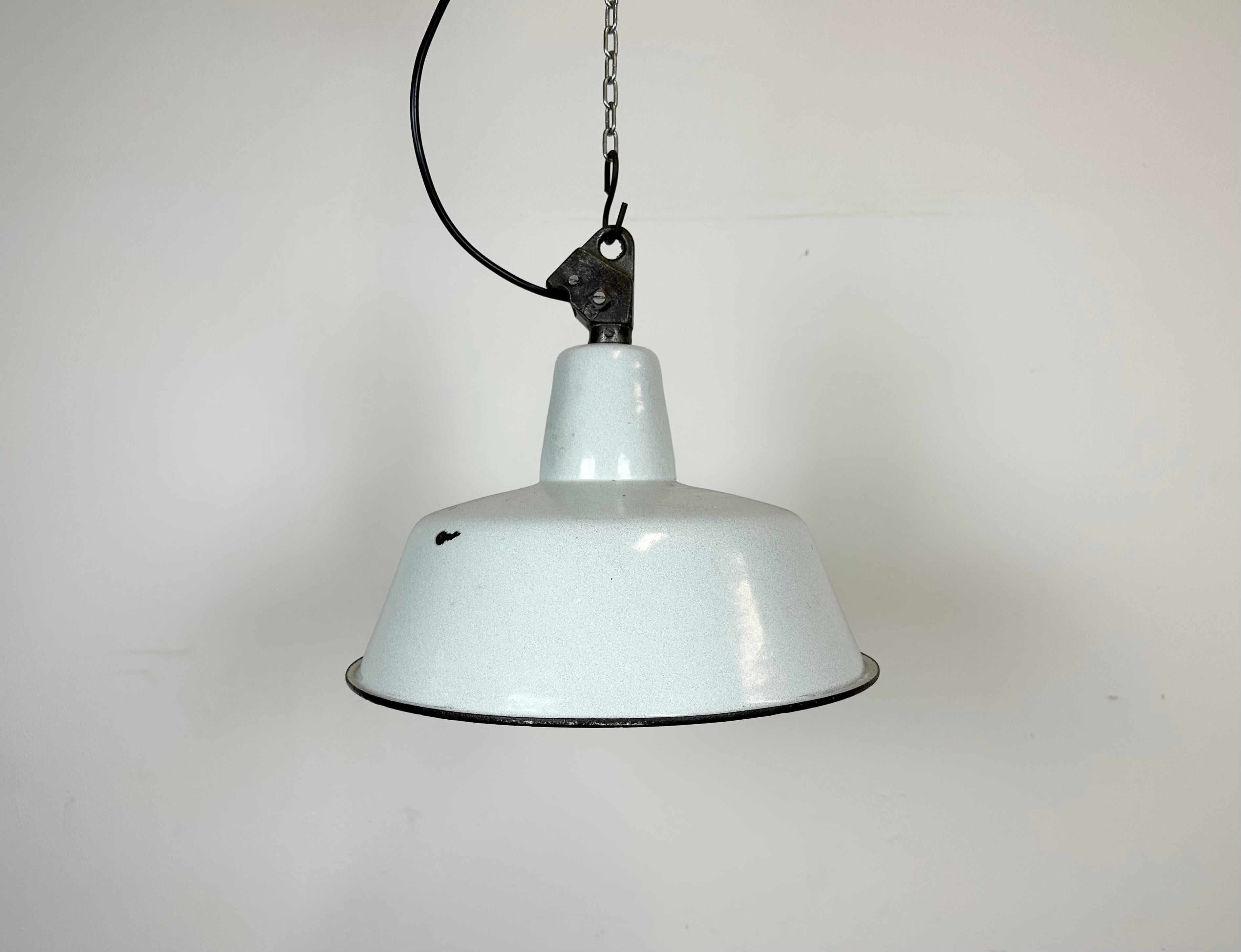 Industrial white (light grey) enamel pendant light made by Polam Wilkasy in Poland during the 1960s. White enamel inside the shade. Cast iron top. The porcelain socket requires E 27/ E 26 light bulbs. New wire. Fully functional. The weight of the