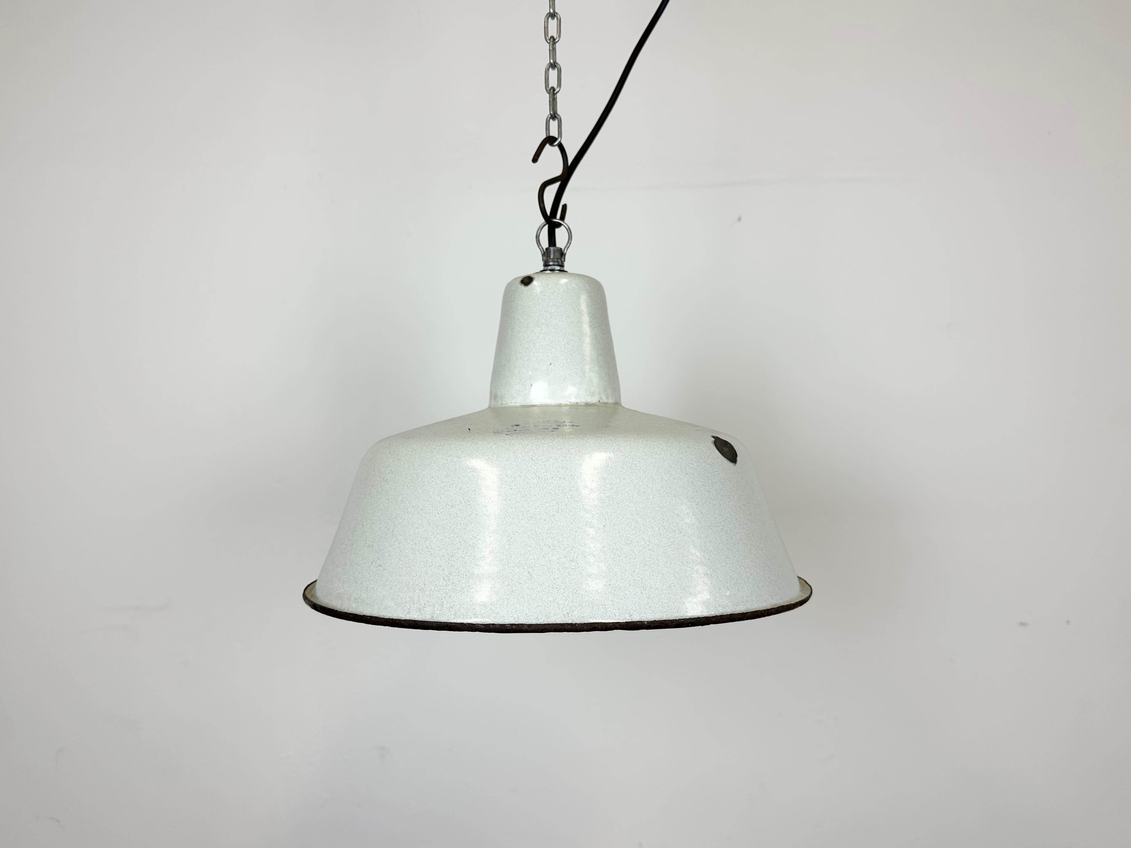 Industrial dark white (light grey) enamel pendant light made by Zaos in Poland during the 1960s. White enamel inside the shade. Iron top. The porcelain socket requires E 27/ E 26 light bulbs. New wire. Fully functional. The weight of the lamp is 1,2