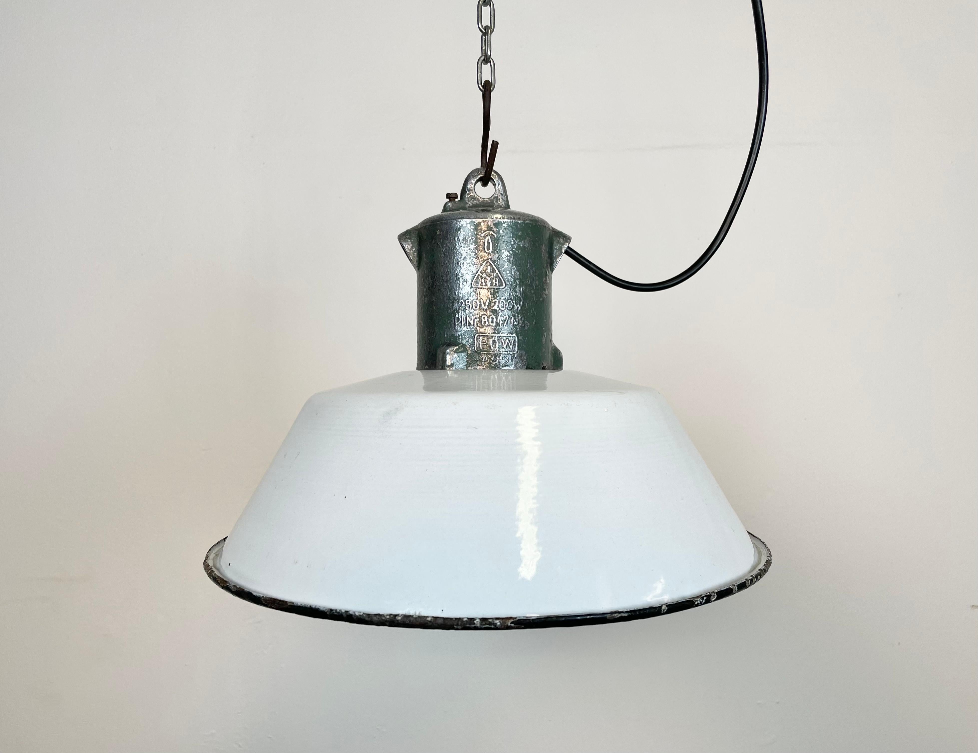 Industrial white enamel pendant light made by EOW in former East Germany during the 1950s. White enamel inside the shade. Cast aluminium top. The original porcelain socket requires E 27/ E 26 light bulbs. New wire. Fully functional. The weight of