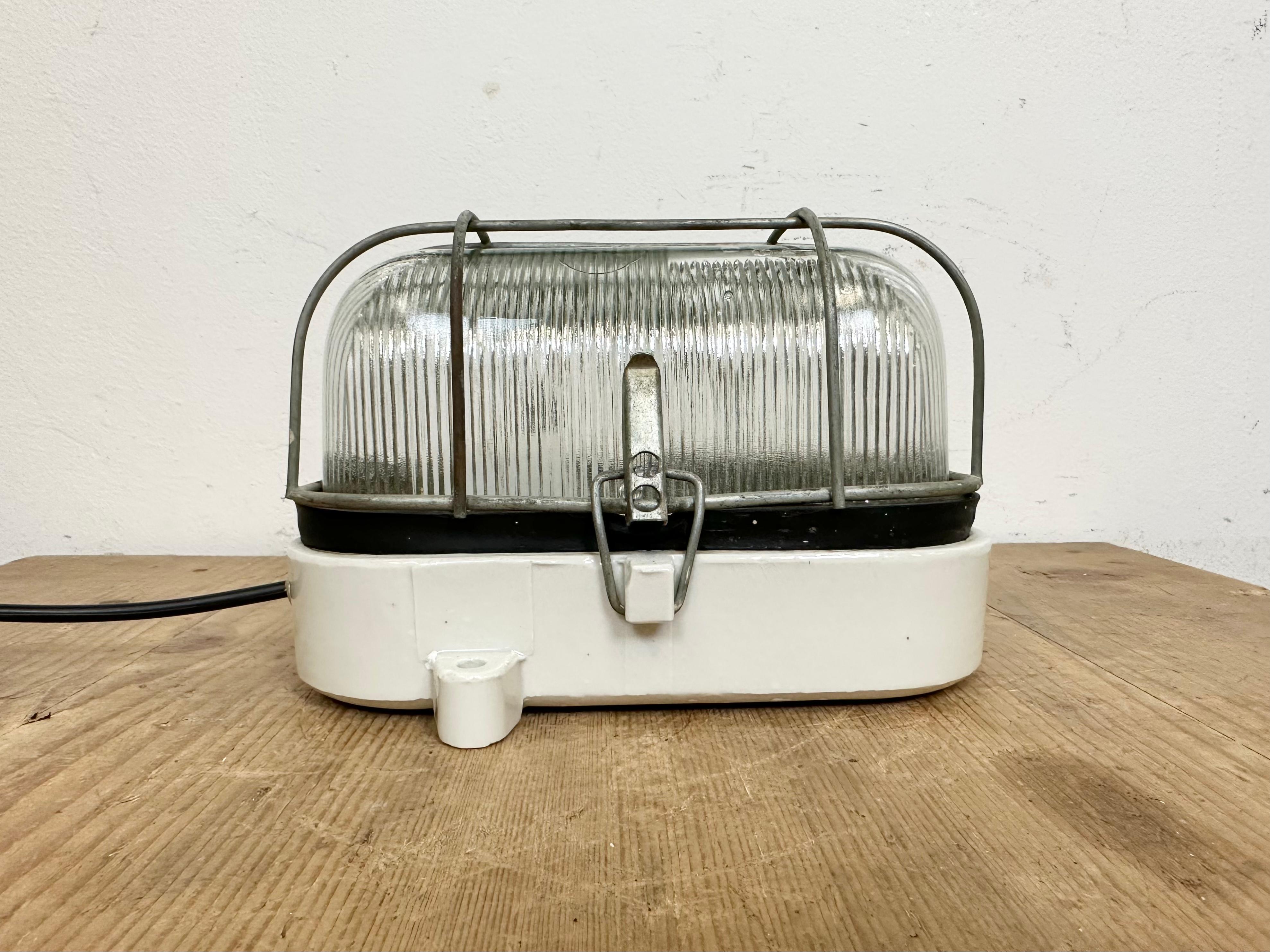 Vintage industrial light made in Poland during the 1970s. It features a white porcelain body and a ribbed glass cover. The socket requires E27/ E26 light bulbs. New wire. The weight of the light is 2.3 kg.