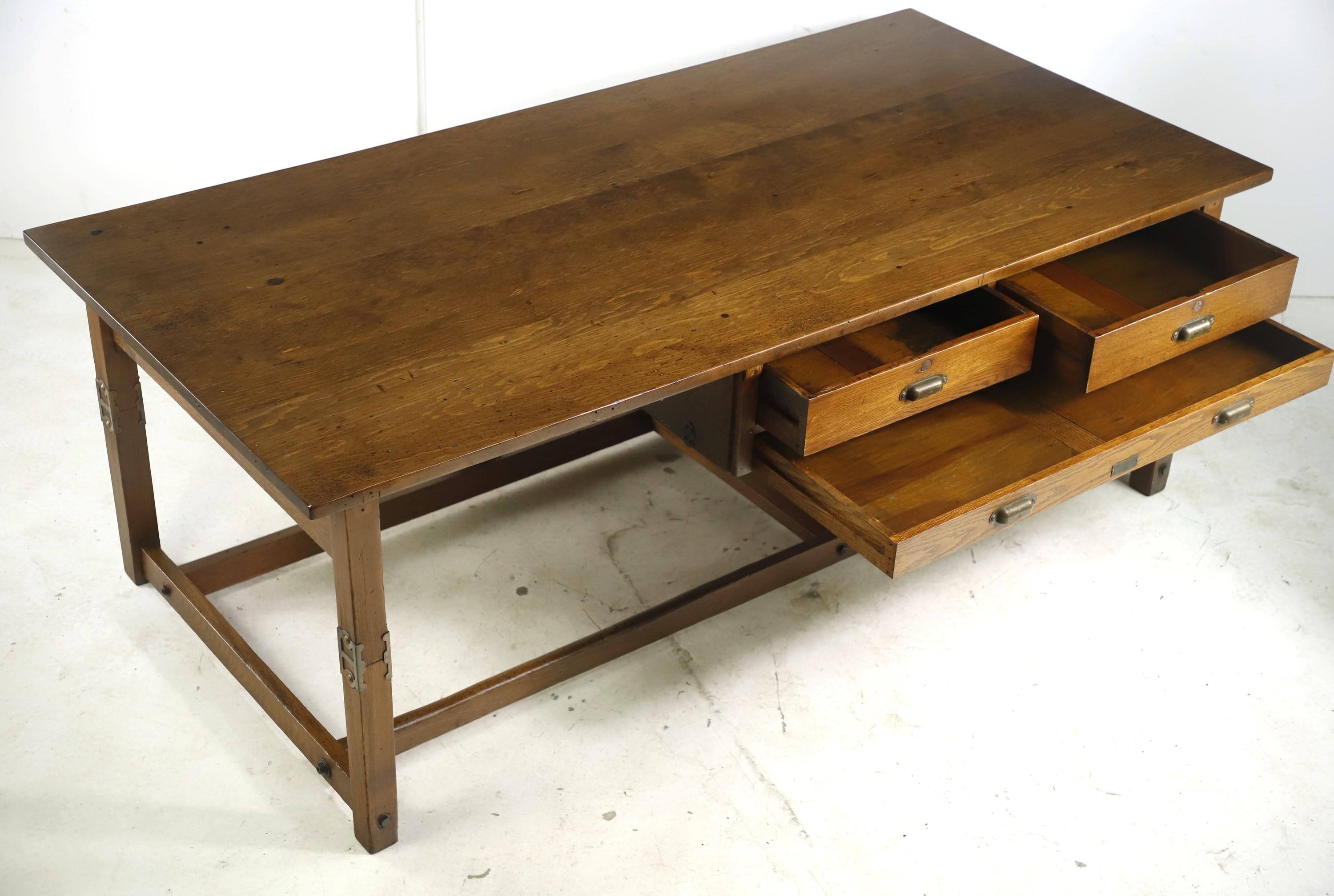 Large Industrial style early 20th century architect drawing table featuring an oak base and a pine top. Comes with three drawers, including one larger blueprint drawer, two regular drawers and original brass hardware. Manufactured by The Keuffel and
