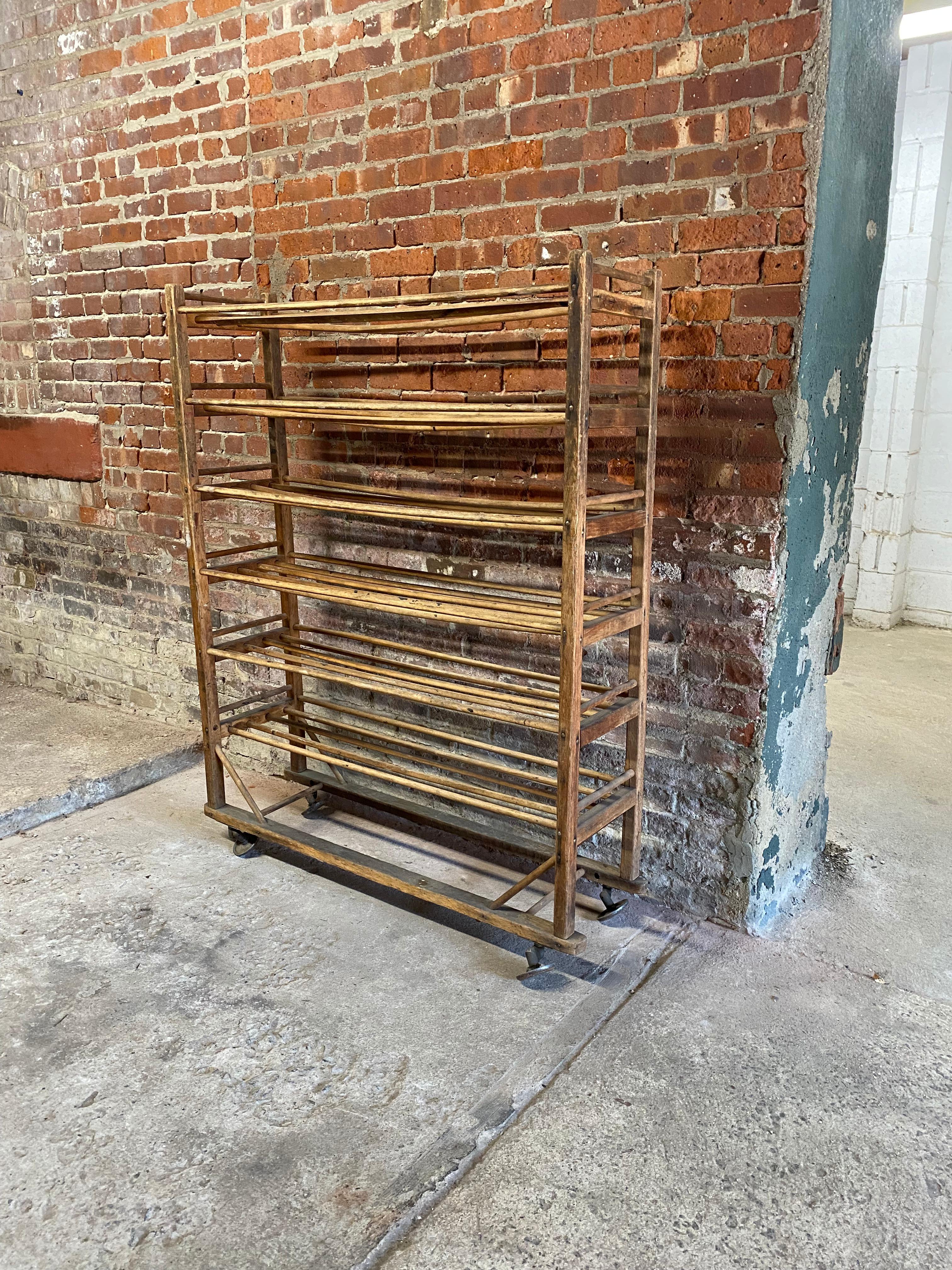 Industrial wood rolling rack with dowel rod shelving. Structurally sound and sturdy design. The shelvings possible previous use was for drying. Circa 1890-1920. Fair overall condition with some sagging or bowing wood dowels. Wood is distressed and