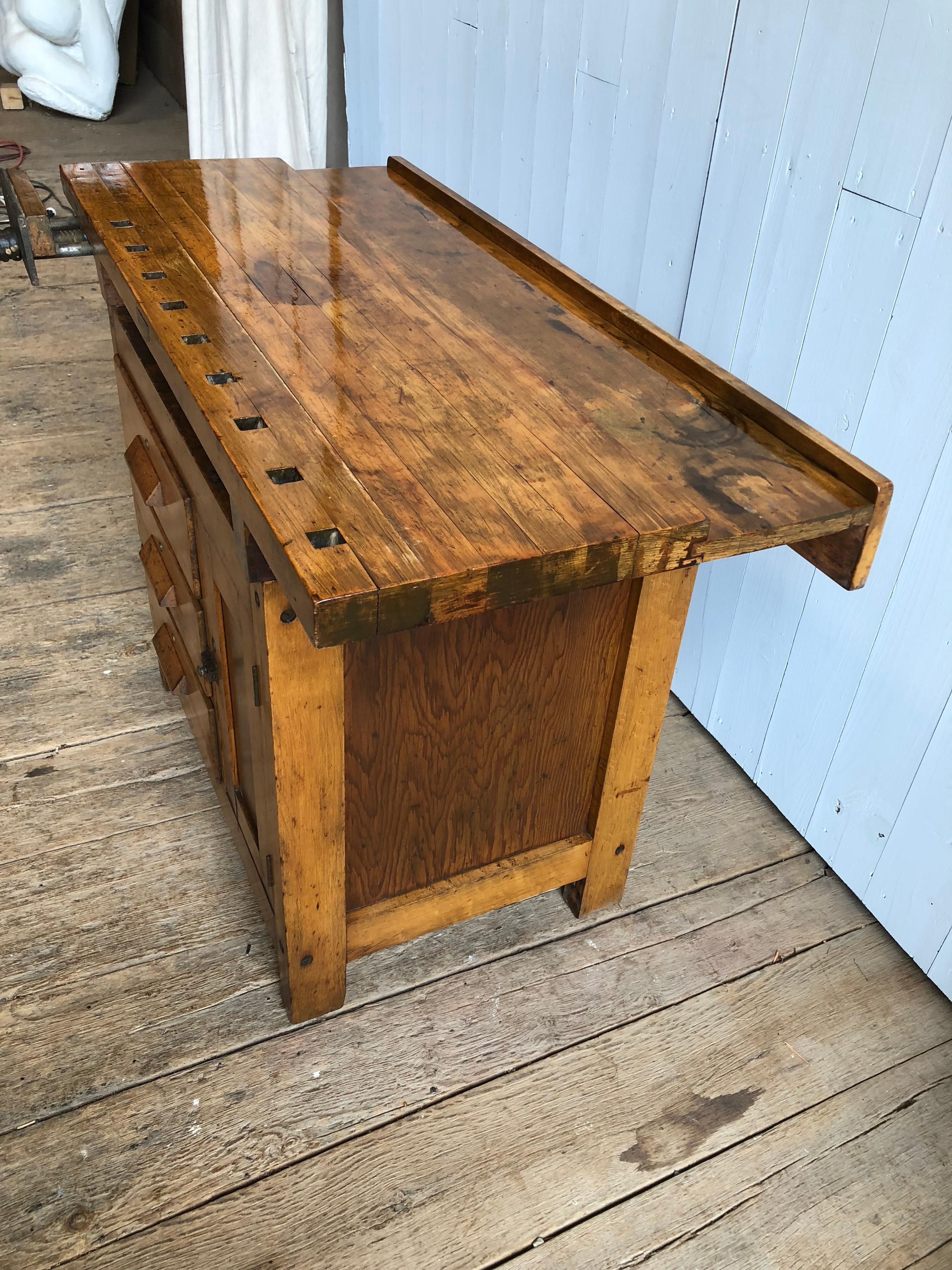 An unusual small size industrial work bench circa 1930 in maple, with a butcher block top, a vice clamp, 3 large drawers and a storage cabinet. Would be perfect for a small bar - trays can be stored in the space under the top, bottles in the cabinet