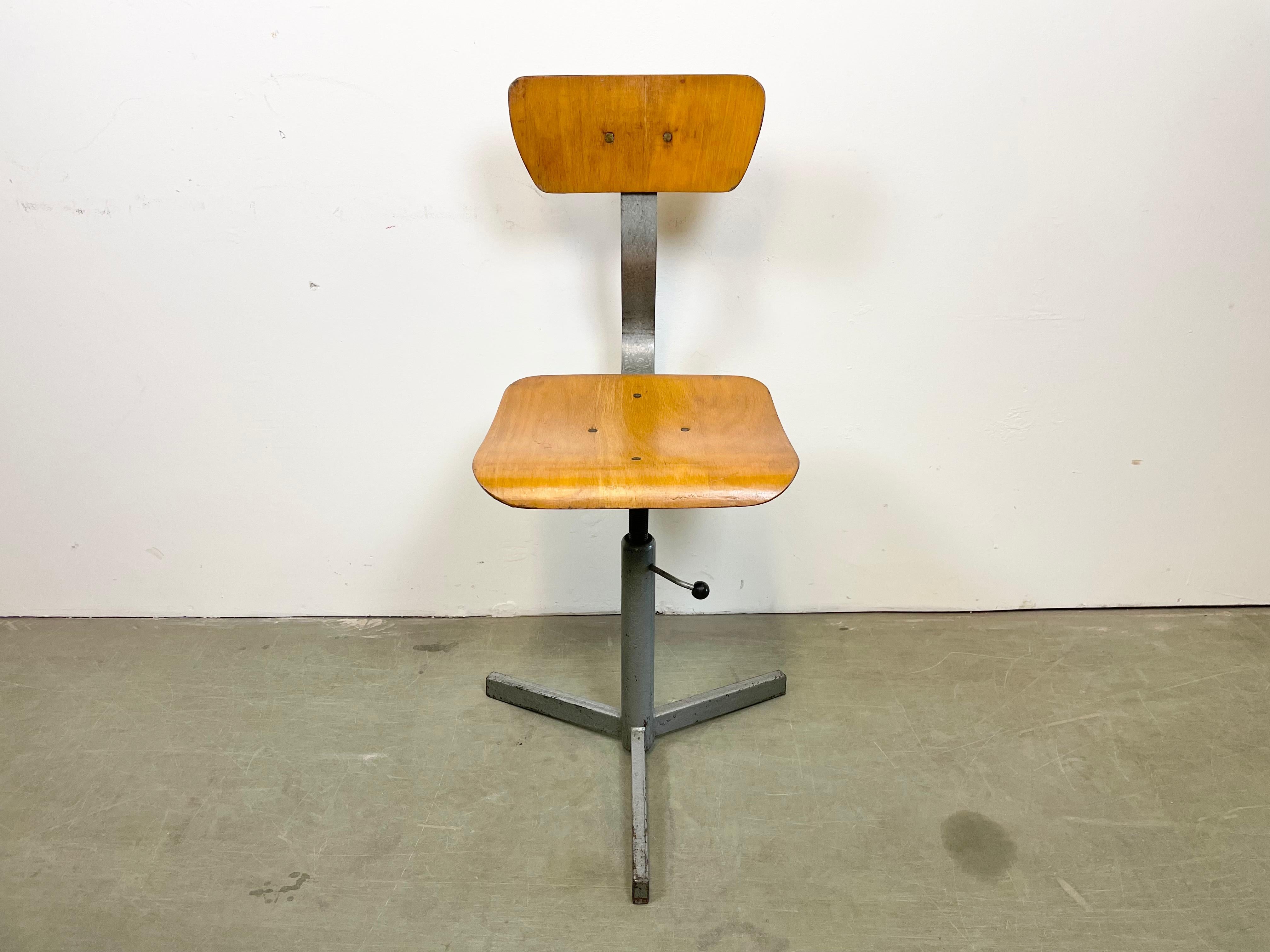 Höhenverstellbarer Industriedrehstuhl, hergestellt in der ehemaligen Tschechoslowakei in den 1960er Jahren. Die Konstruktion besteht aus grau lackiertem Eisen und hat eine Sitzfläche und Rückenlehne aus Sperrholz. Der Stuhl ist in sehr gutem
