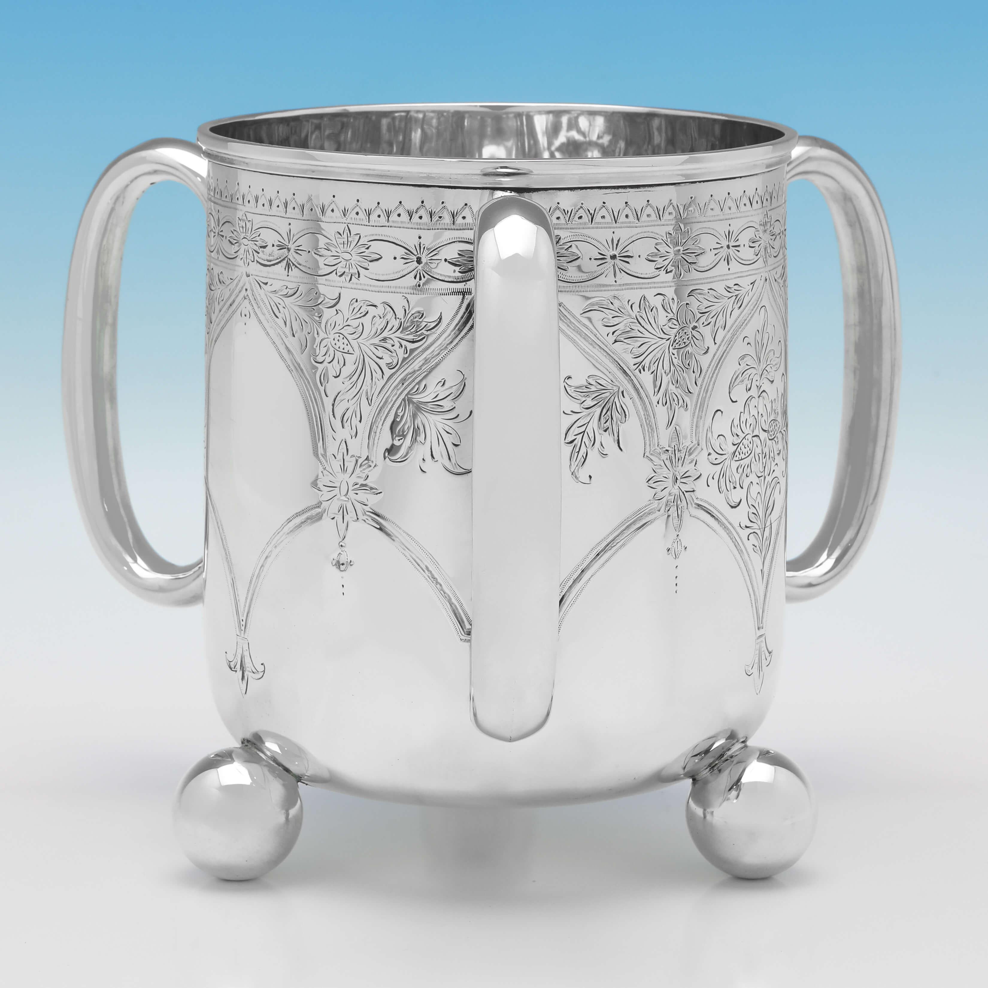 Hallmarked in London in 1881 by Aldwinckle & Slater, this striking, Victorian, antique sterling silver cup, features 3 handles, engraved decoration to the body, and stands on three ball feet. 

The cup would make an ideal wine cooler for a single