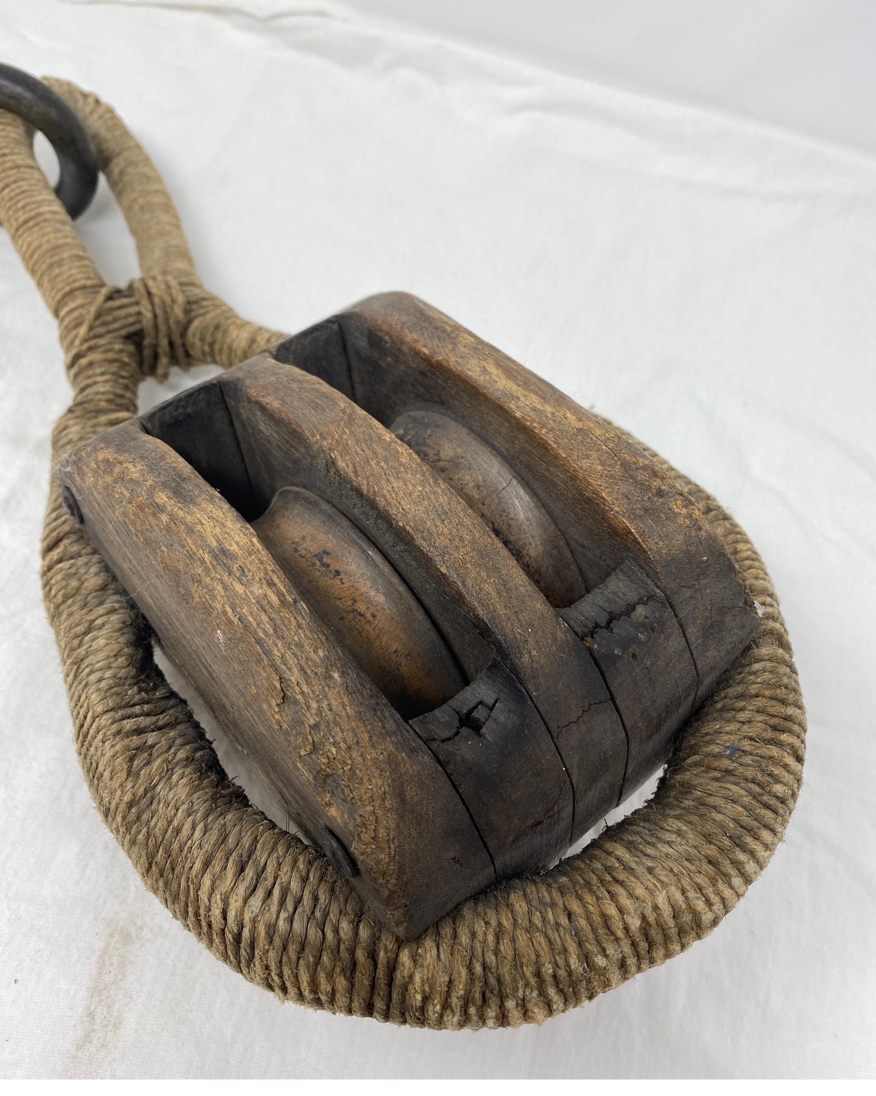 Industrial pulley with a forged iron hook. The pulley itself is wood and with rope wrapping.