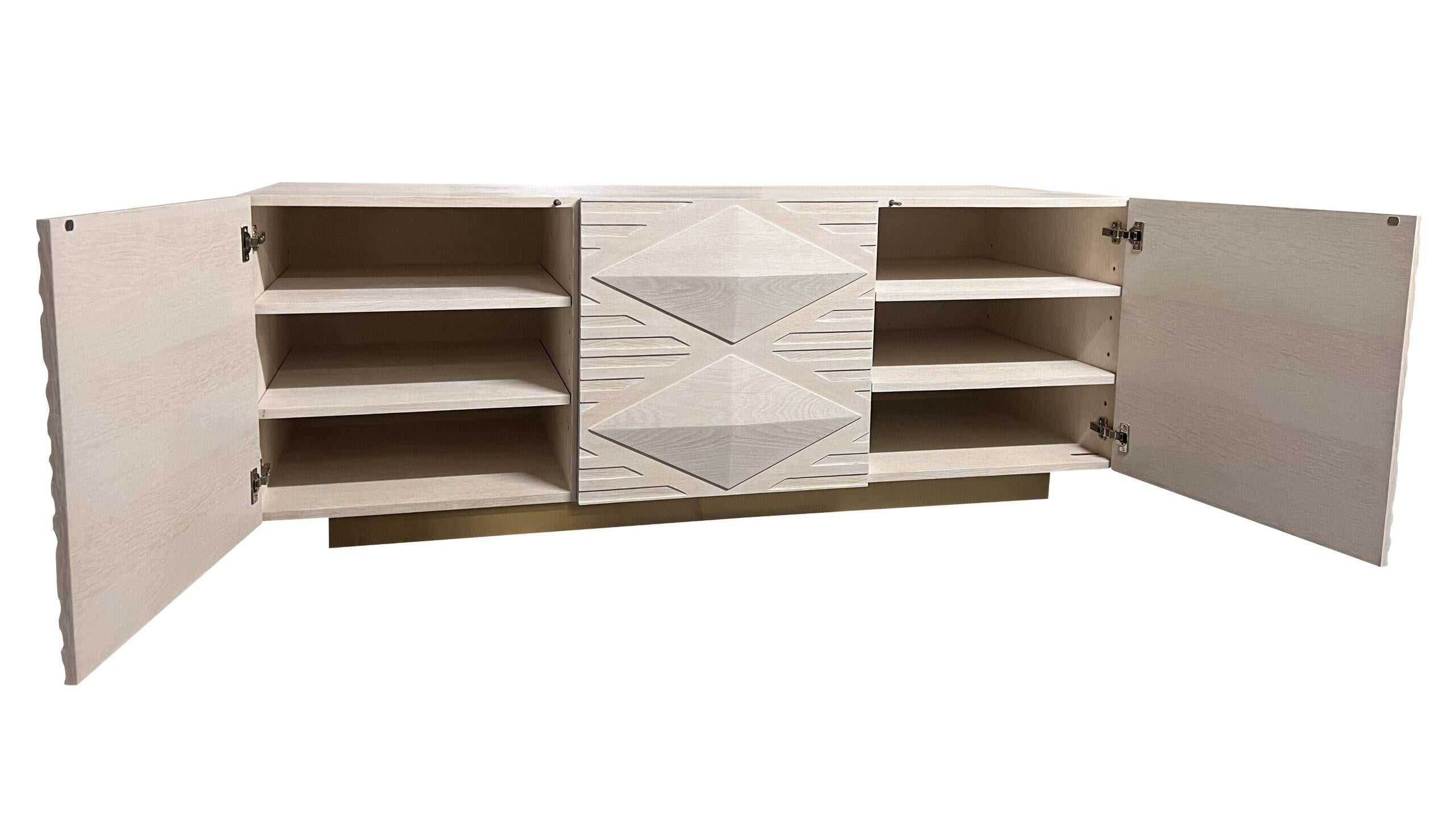 INES BUFFET CABINET - Modernes, gebleichtes Eichenholz mit handgeschnitztem Design und satiniertem Messing-Metallsockel. QTY 2 verfügbar. 

Der Buffetschrank Ines ist ein atemberaubendes Möbelstück mit einem Korpus aus gebleichter Weißeiche mit