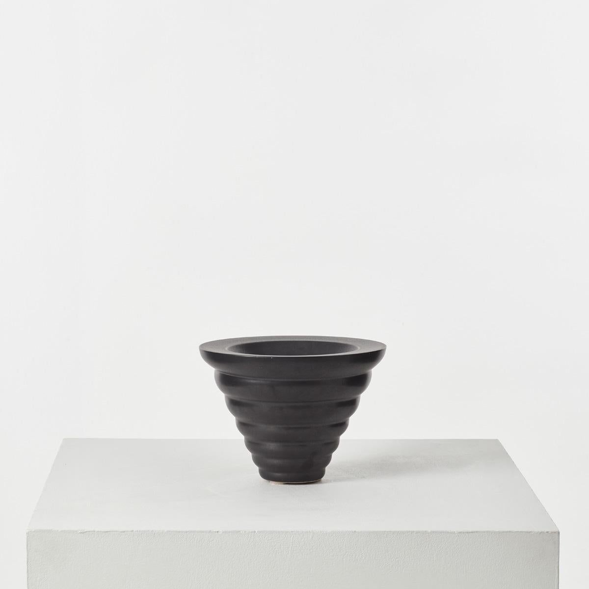A black glazed vase or bowl by Dutch designer Ines Van der Sluis. It has a distinct rippled conical form, finished in an off-black glaze.

In good vintage condition. One marked underside with the artist’s name and ‘Designum,’ one not. 

J110b: H21